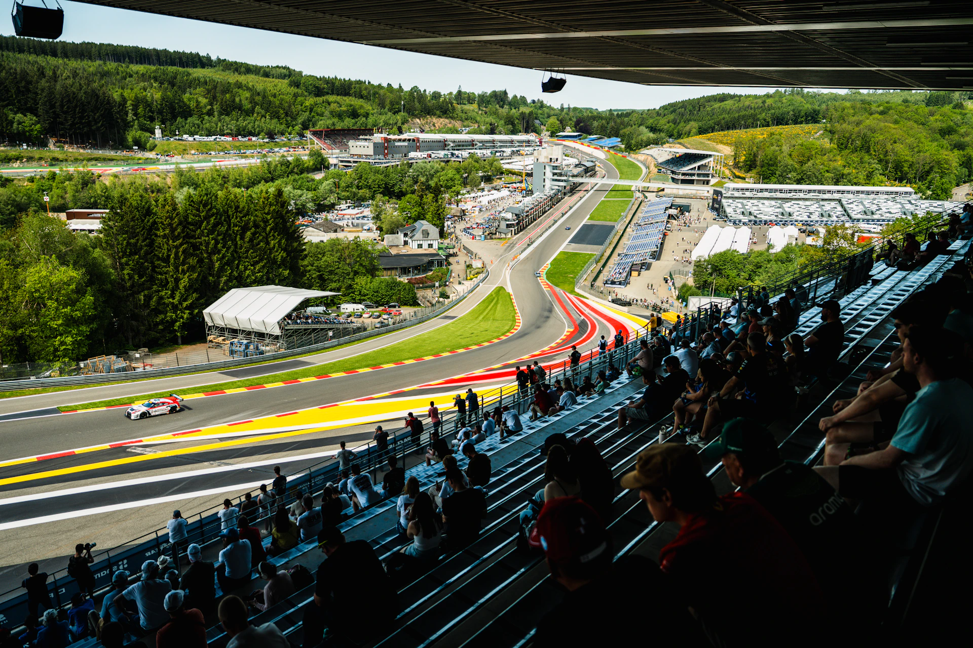 Spectators watch race cars on a winding track.