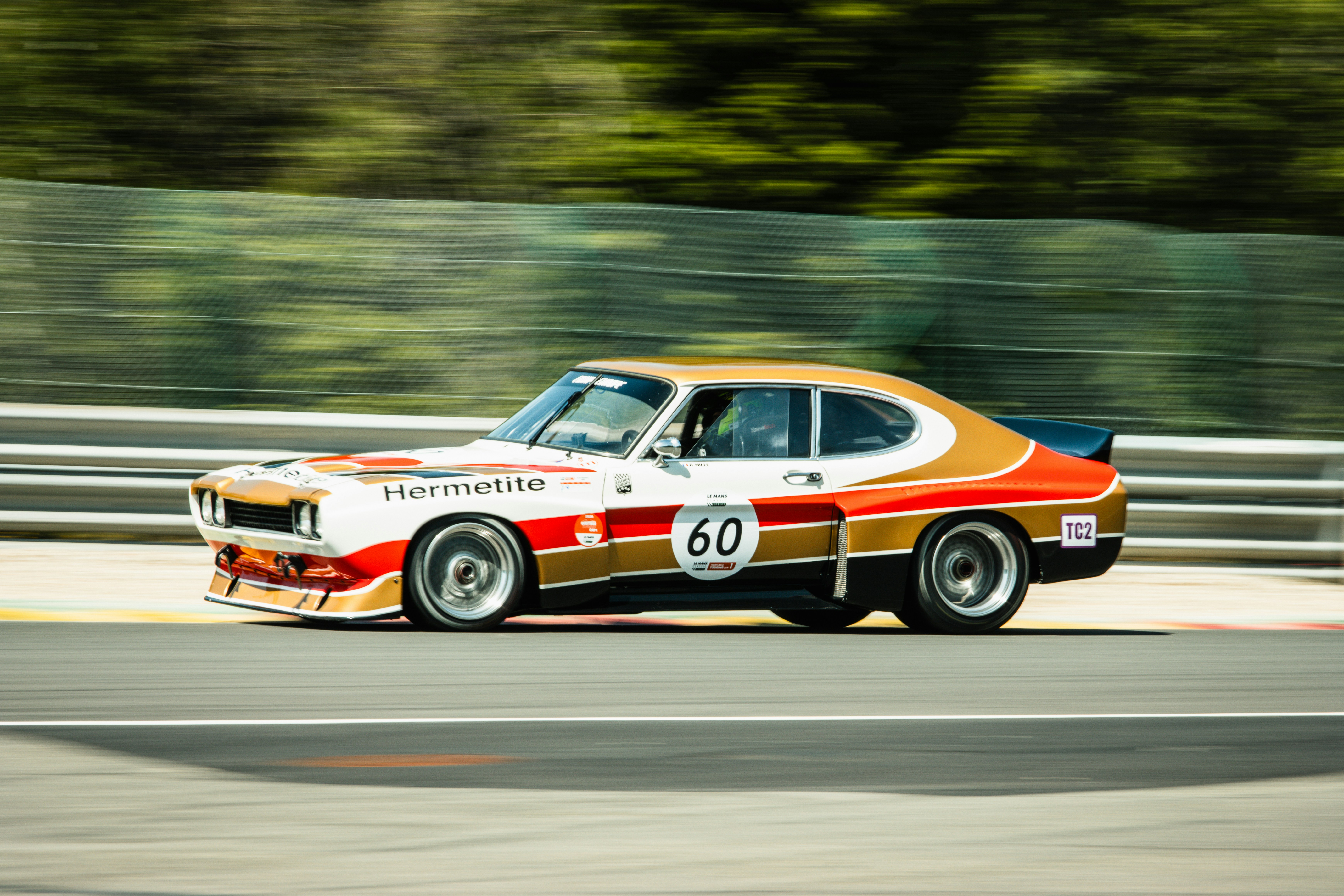 Classic race car with gold and white livery on track.