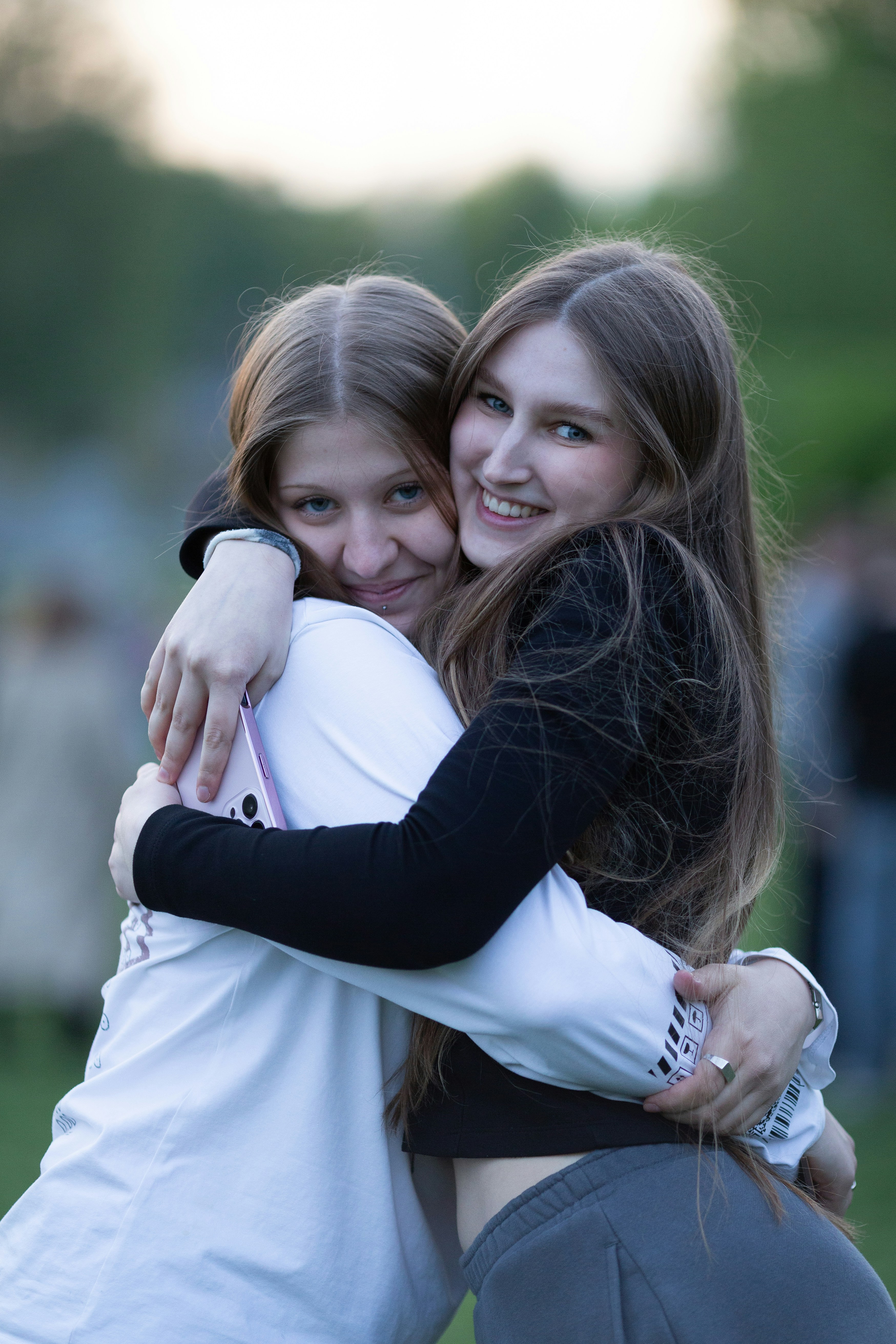 Two young women hugging and smiling outdoors.