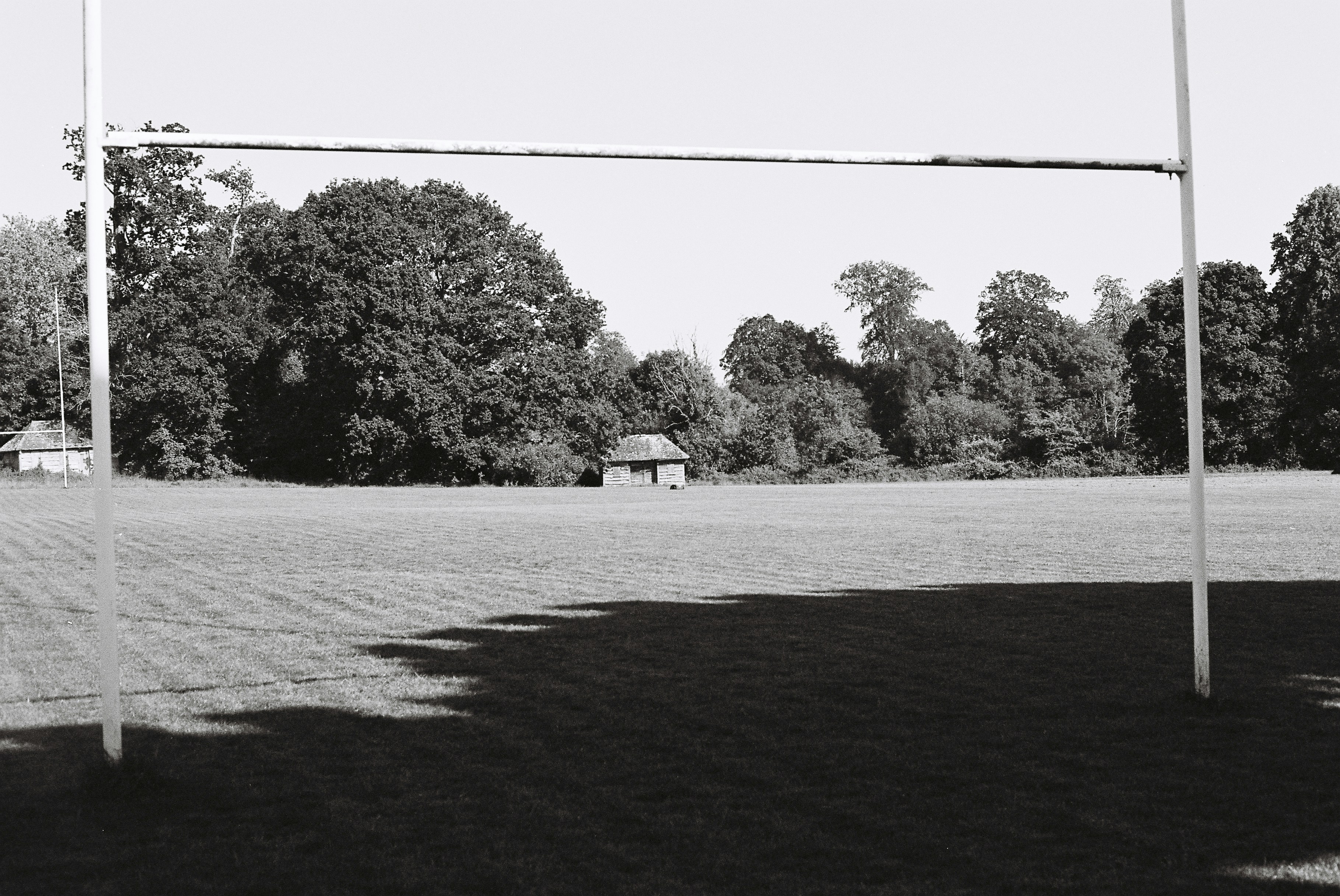 Empty rugby field with goalposts and distant trees.