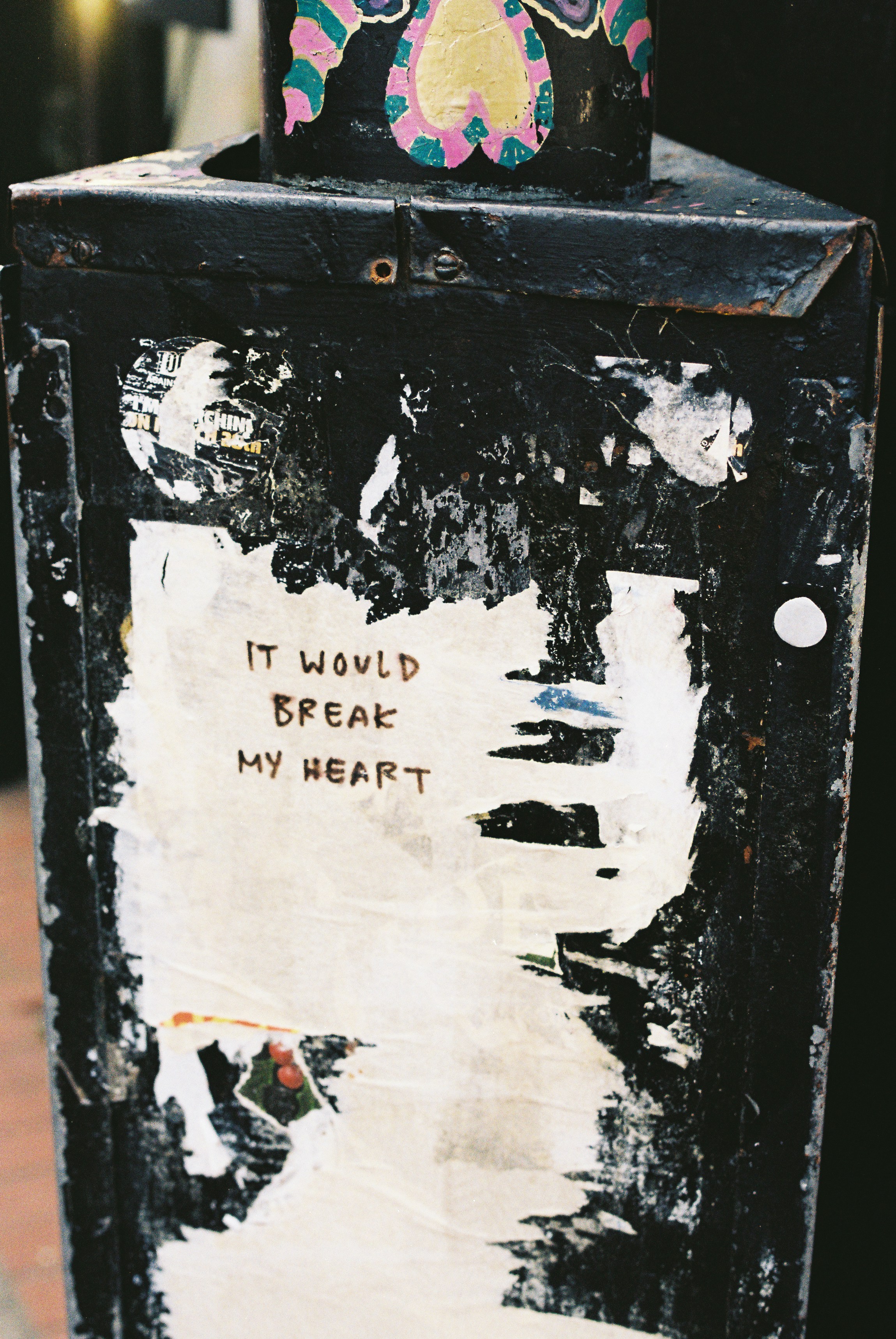 Weathered black pole with 'it would break my heart' text.