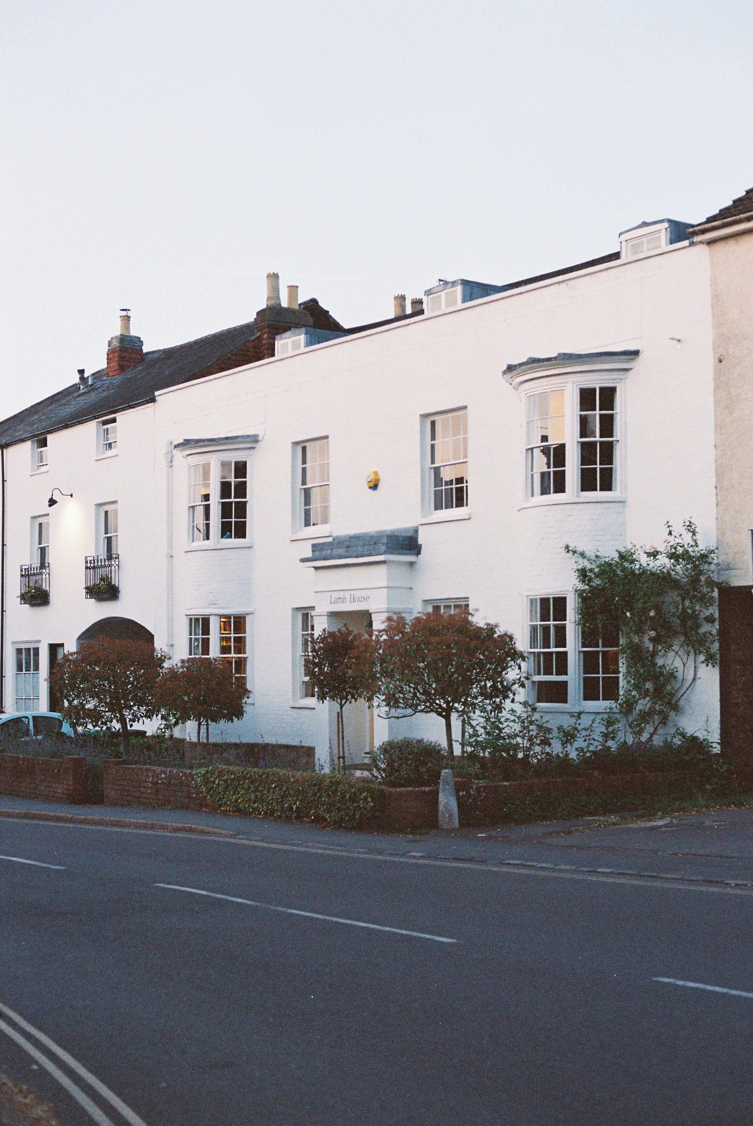 White-painted two-story house with bay windows and a planted front garden