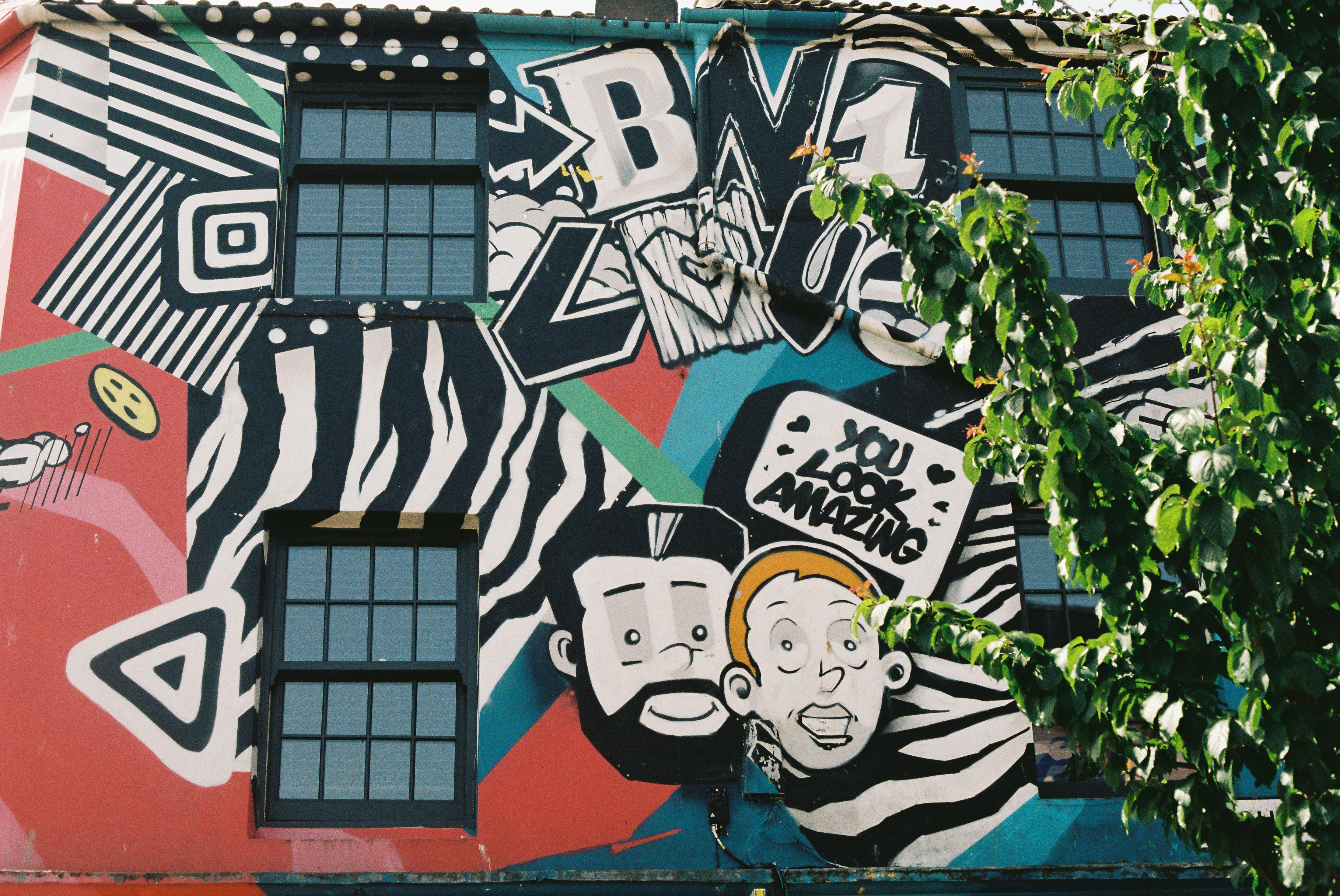 Graphic street art mural with faces and bold patterns
