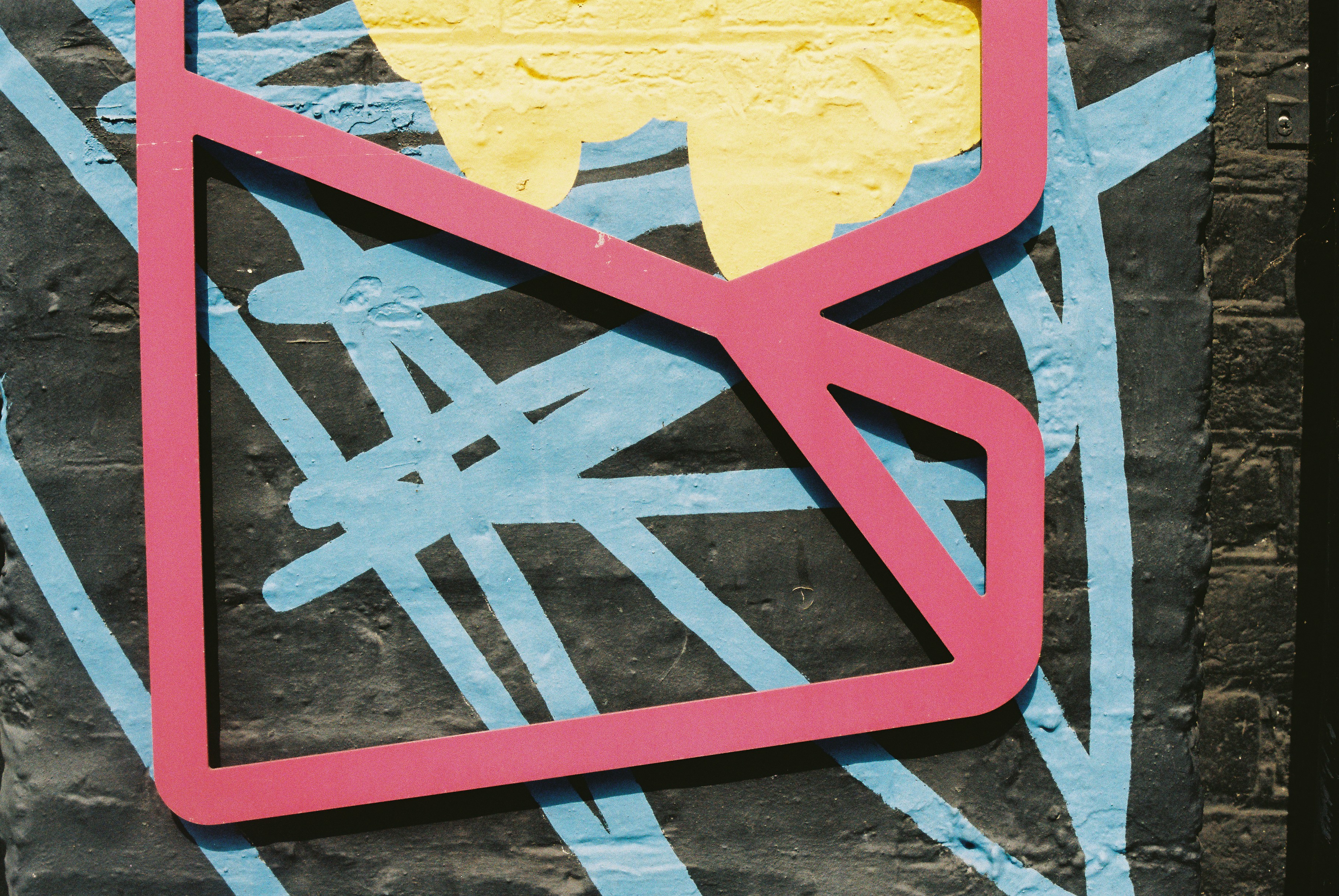 Pink geometric shape on dark background with blue and yellow.
