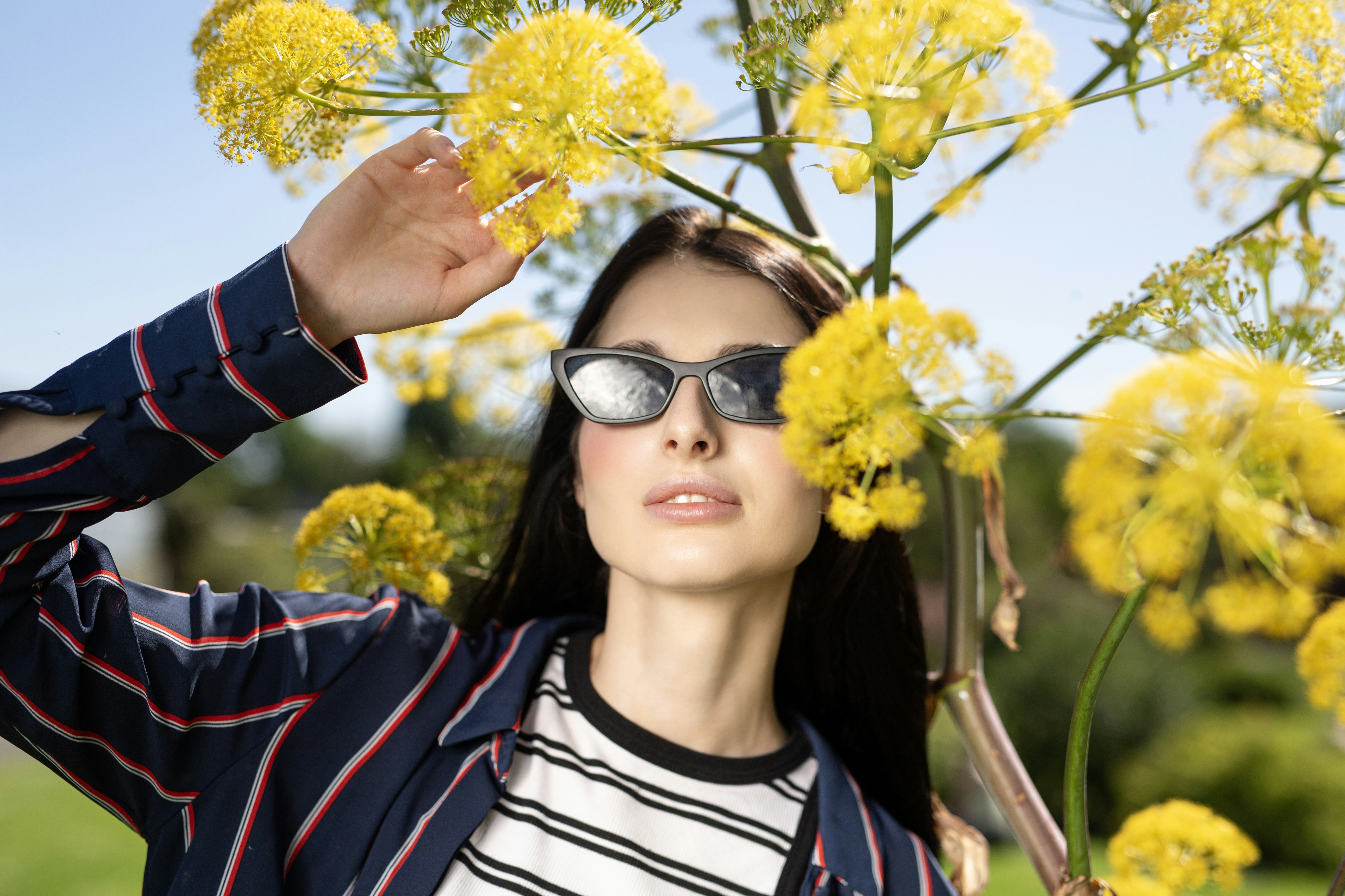 A young woman in sunglasses among vibrant yellow flowers.