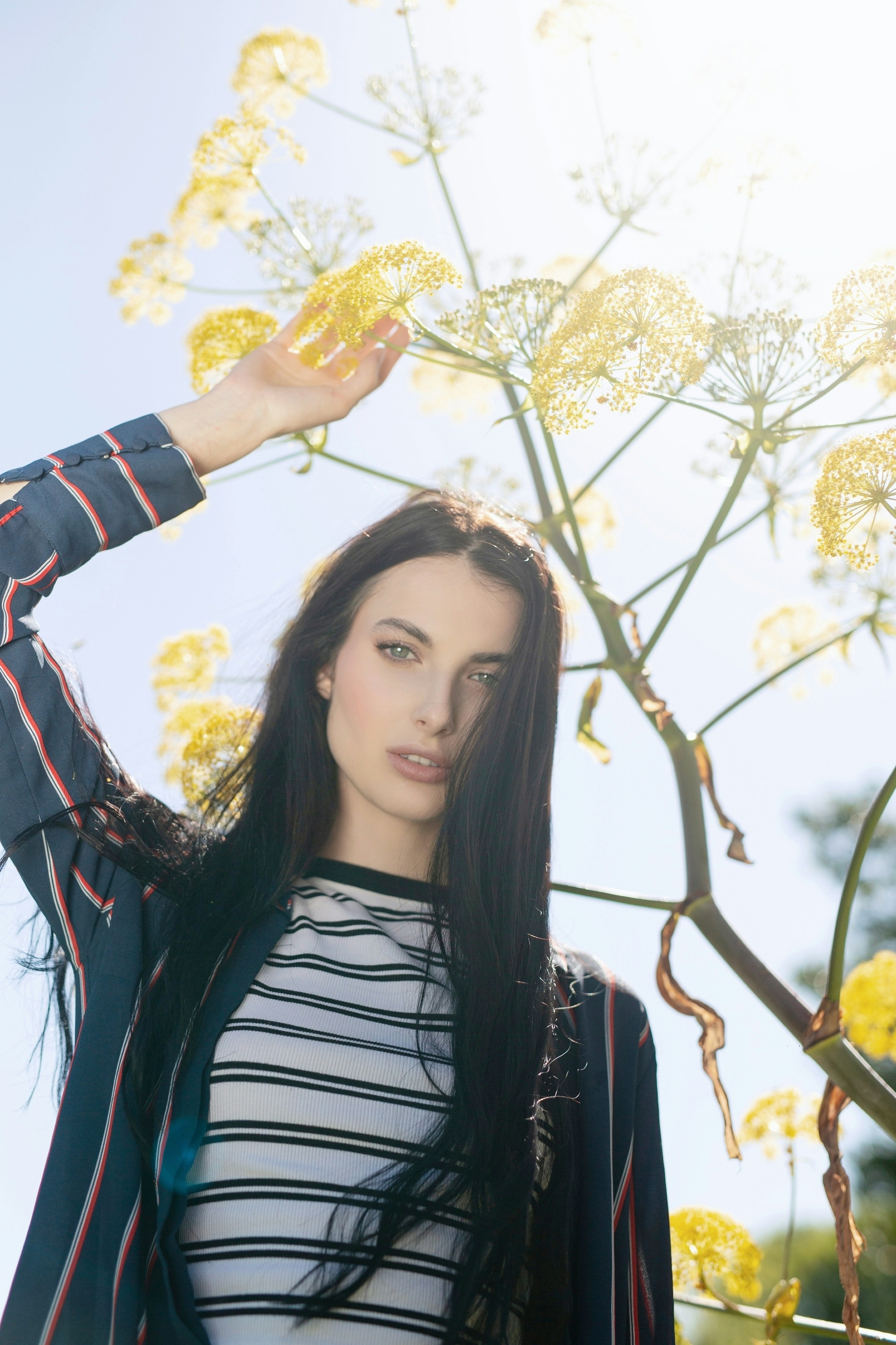 Beautiful woman with long dark hair under yellow flowers.