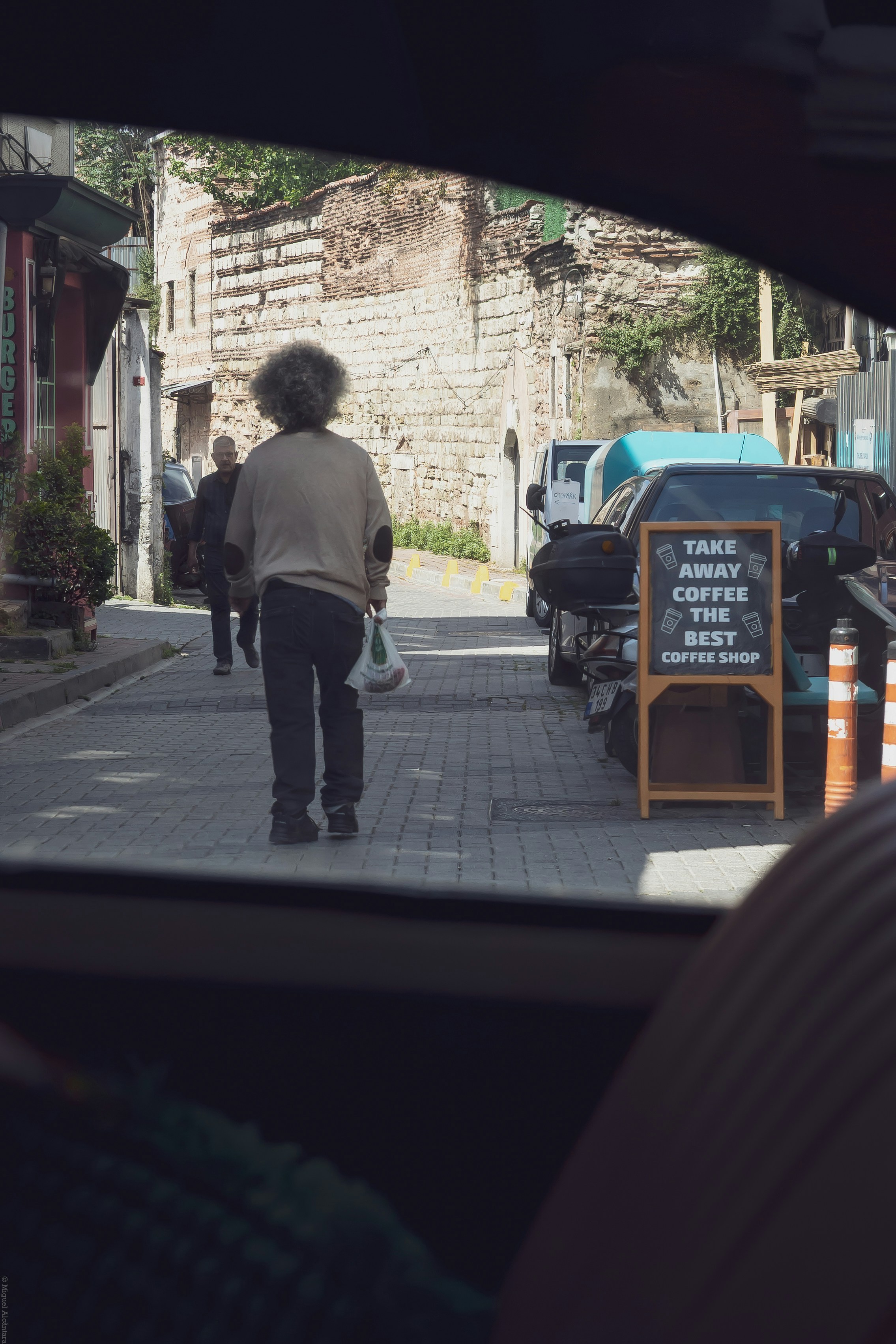 View from car of person walking on old city street.