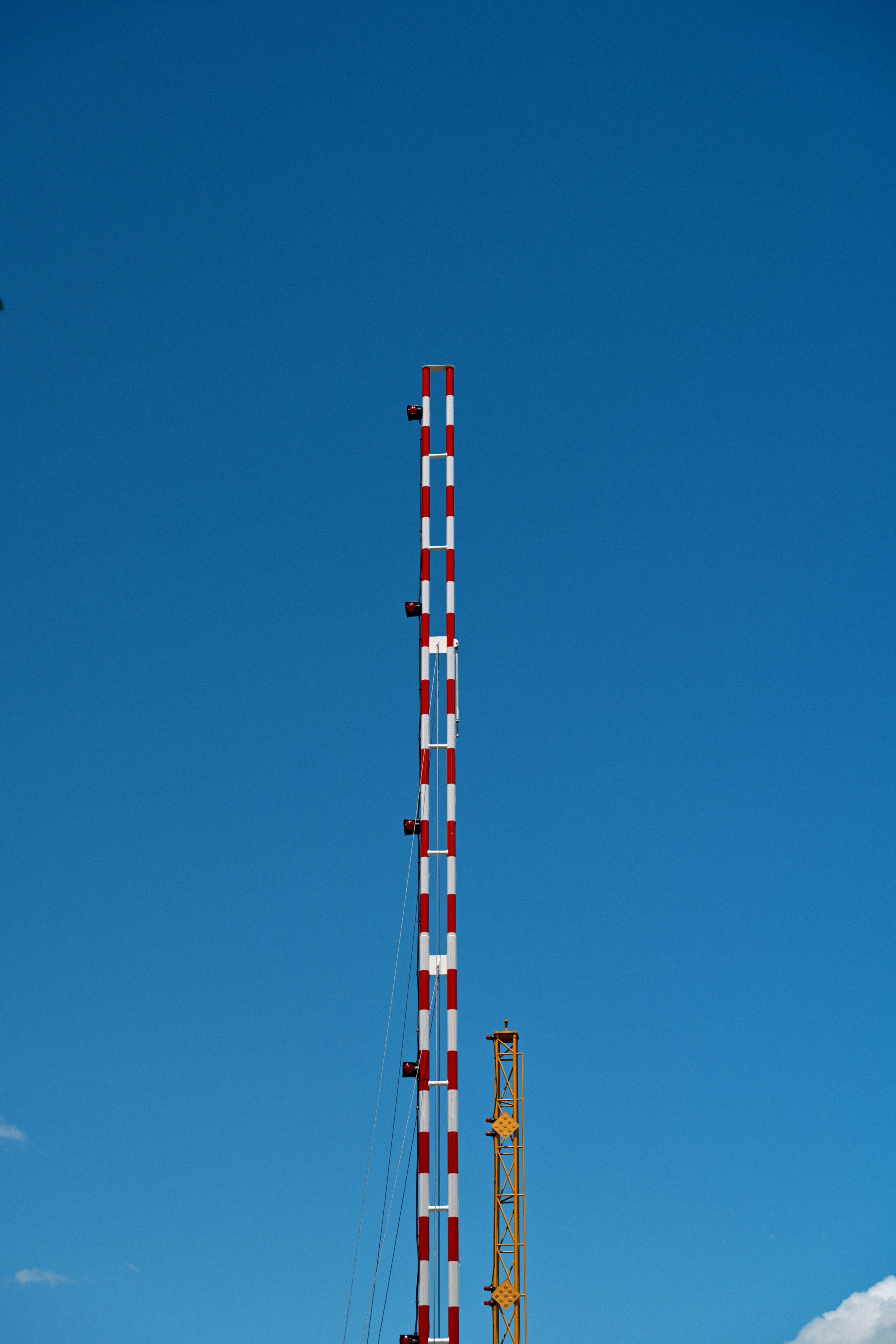 Red and white striped pole against a clear blue sky.