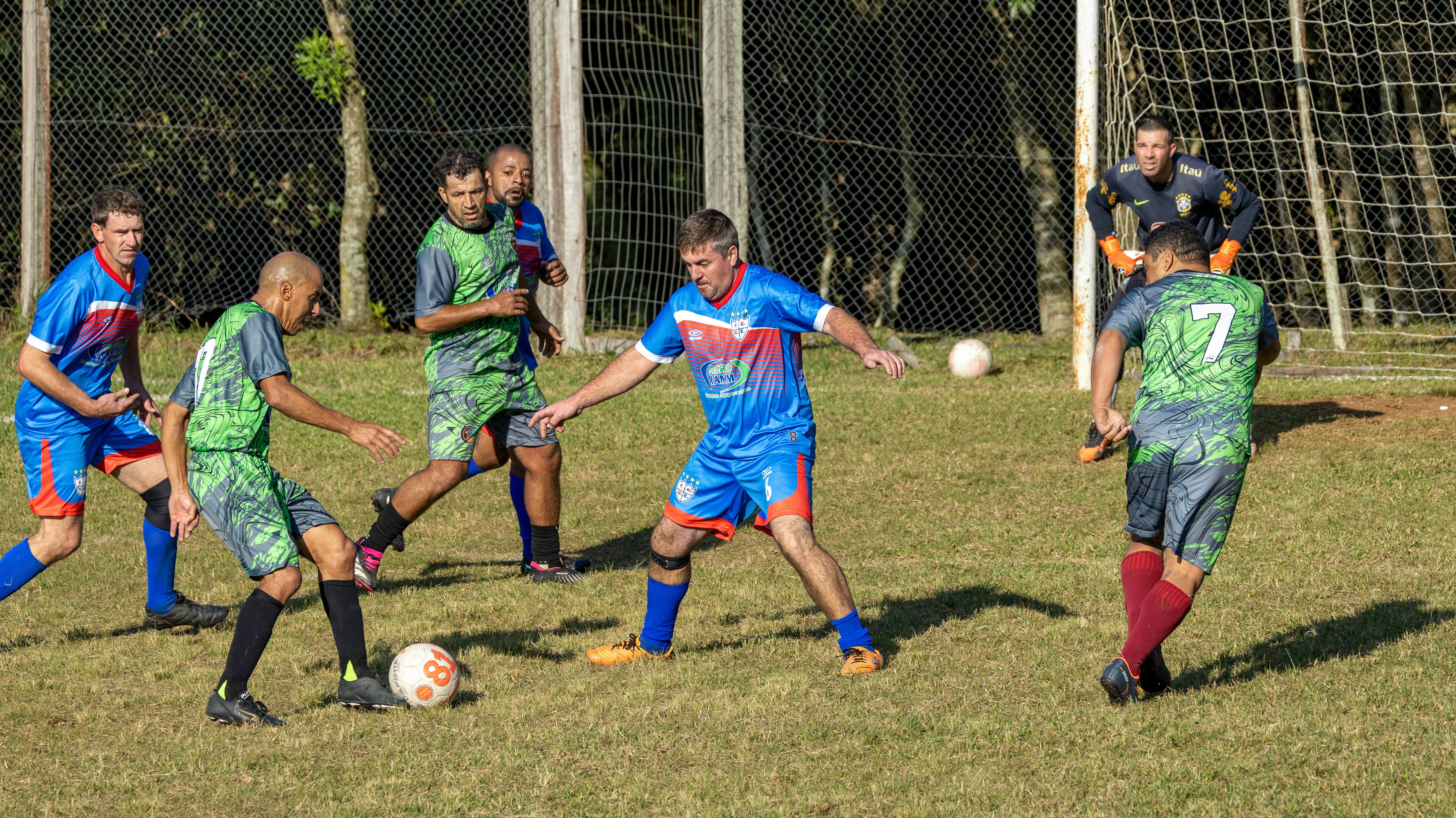 Pria bermain sepak bola di lapangan berumput di siang hari.