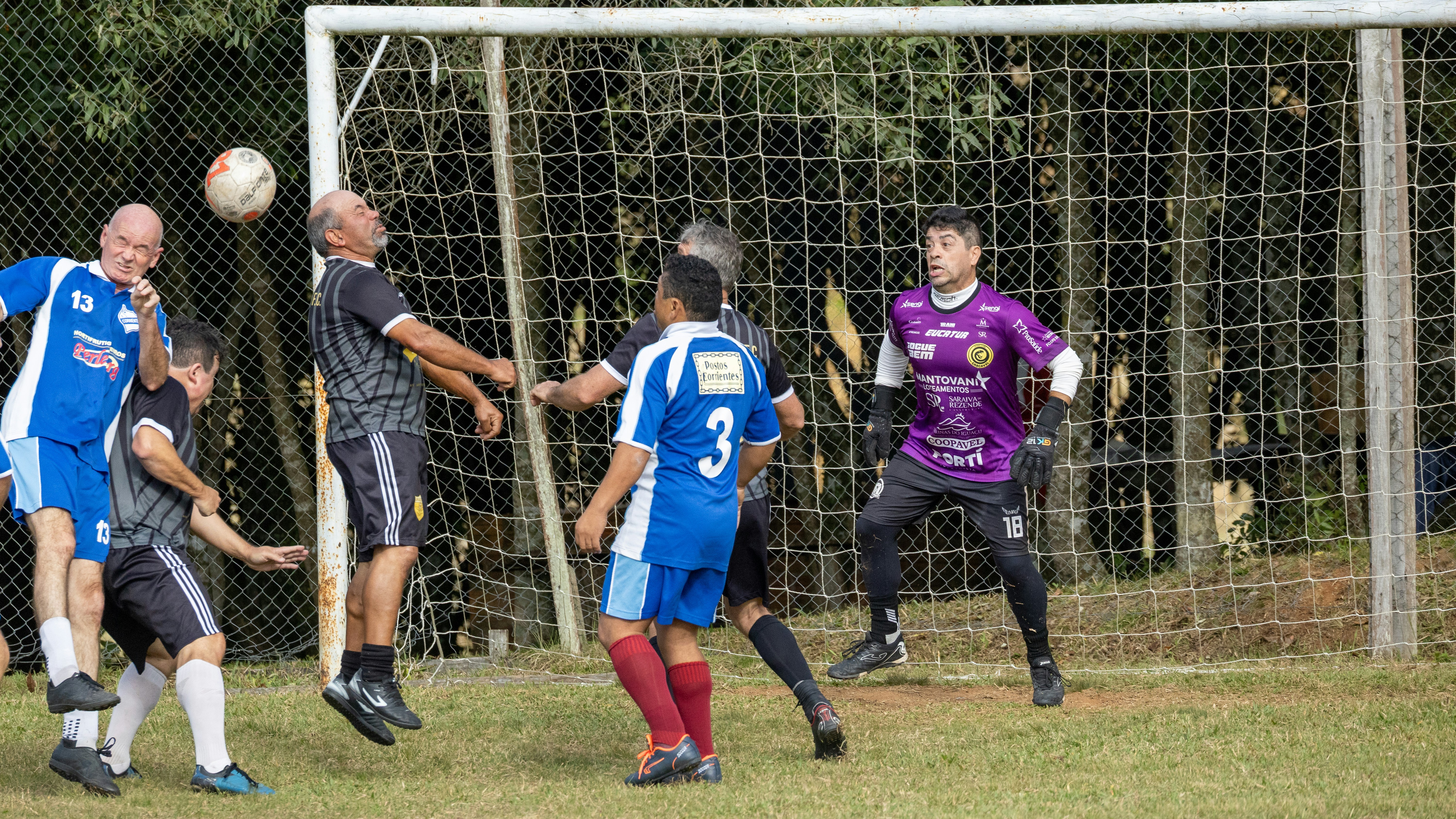 Pria bermain sepak bola di dekat gawang, satu menyundul bola.