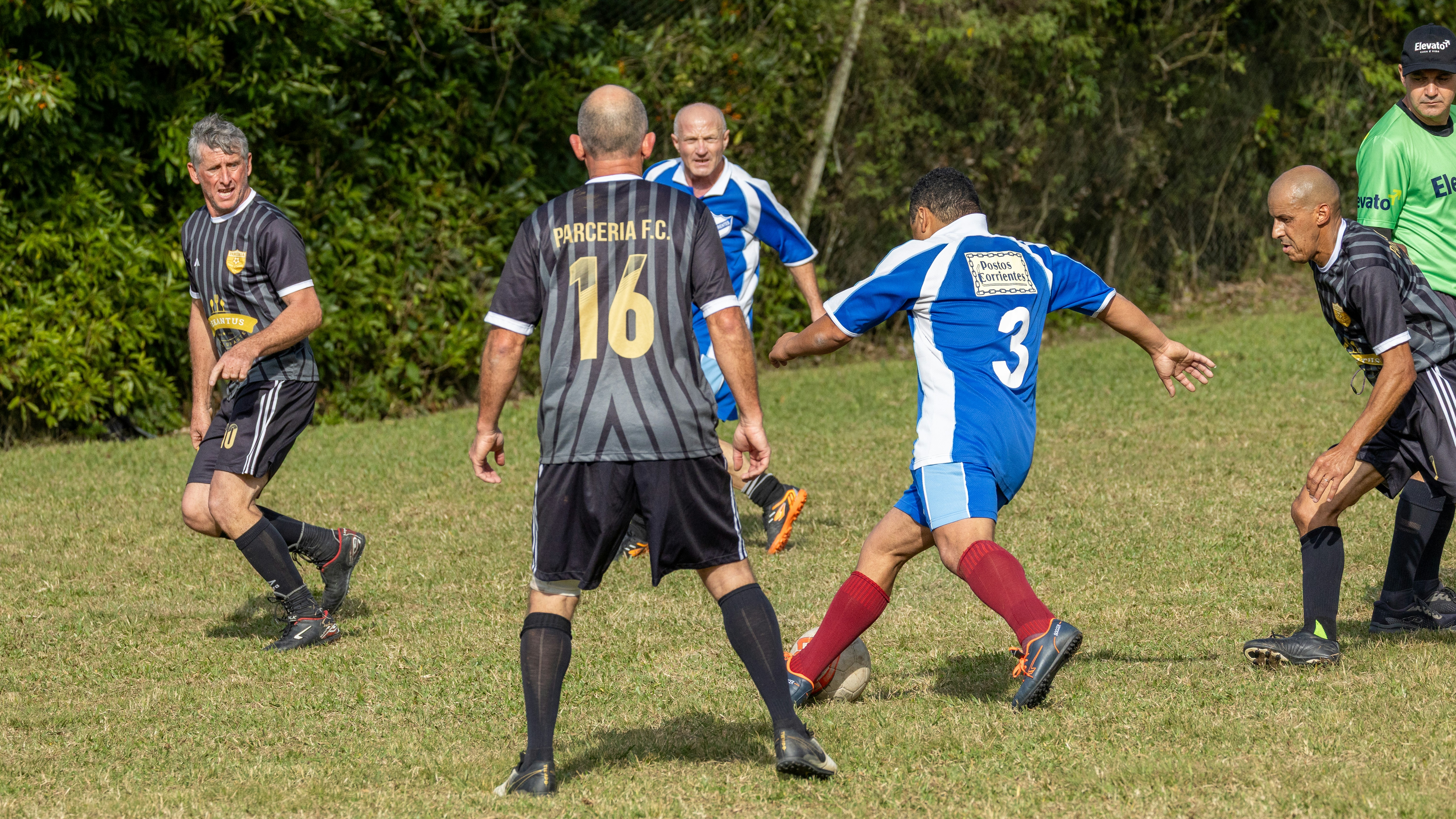 Pria bermain sepak bola di lapangan luar ruangan berumput.