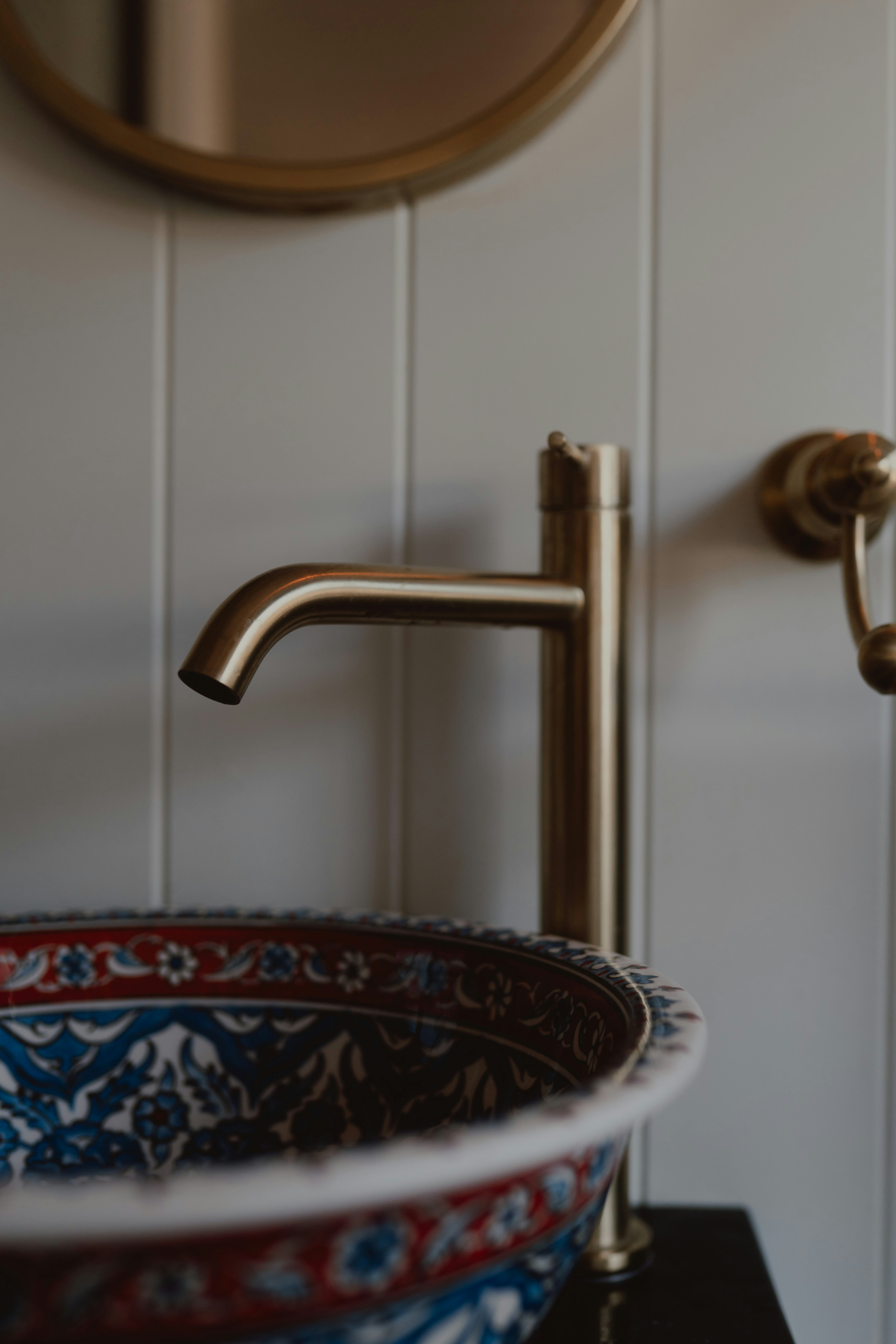 Golden faucet above a decorative ceramic sink with intricate patterns.