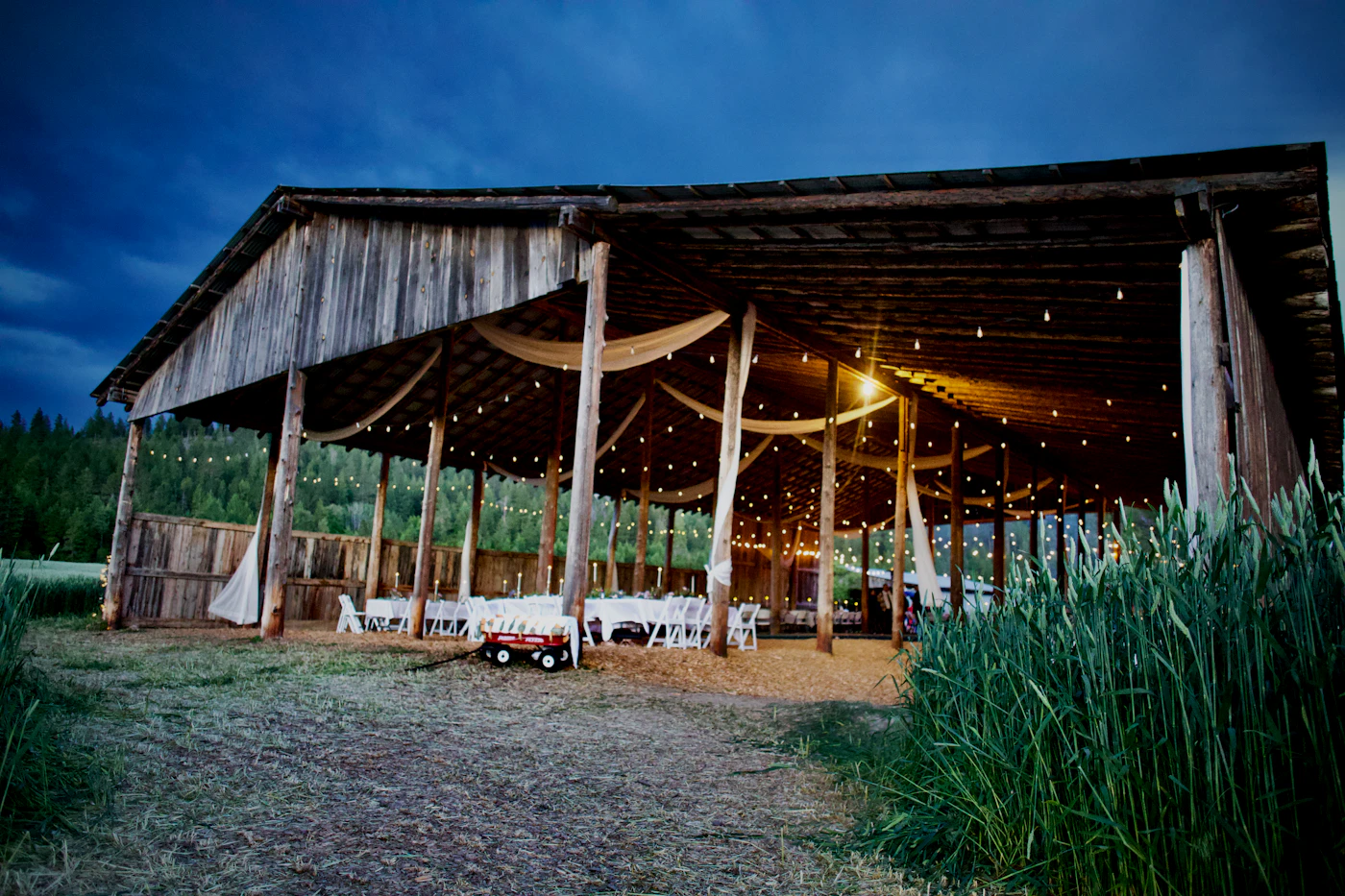 Wedding reception lighting setups for barn venues — A crystal chandelier hung from wooden beams adds elegance to a rustic barn venue.