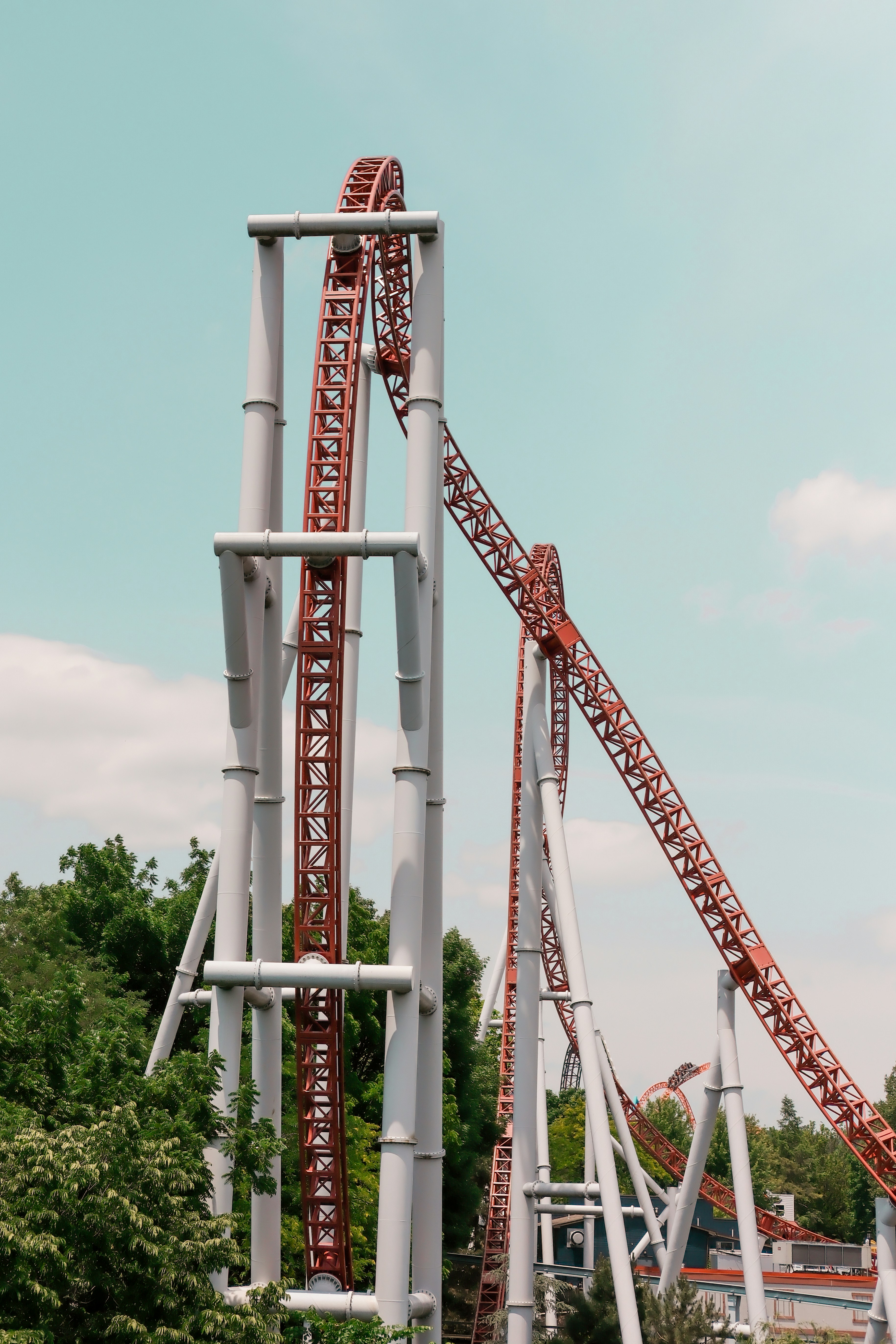 A tall red and white rollercoaster under a clear sky.