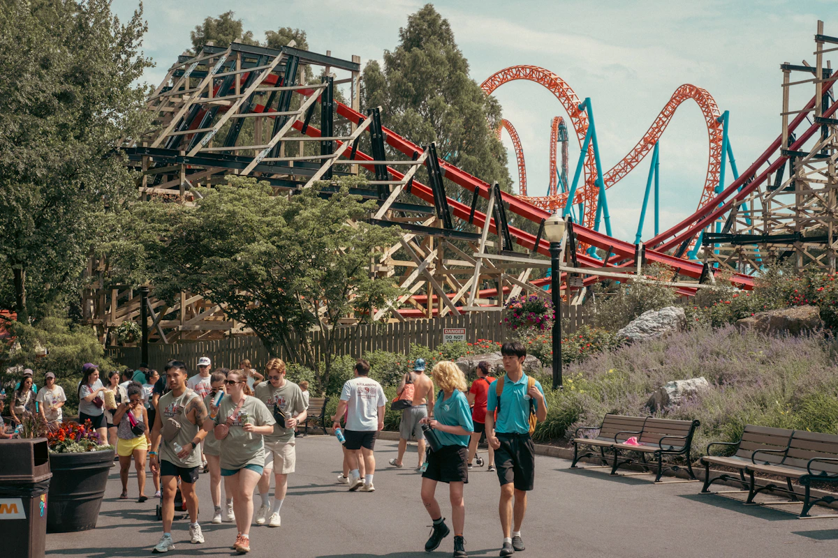 Families walking beside thrilling amusement park roller coasters