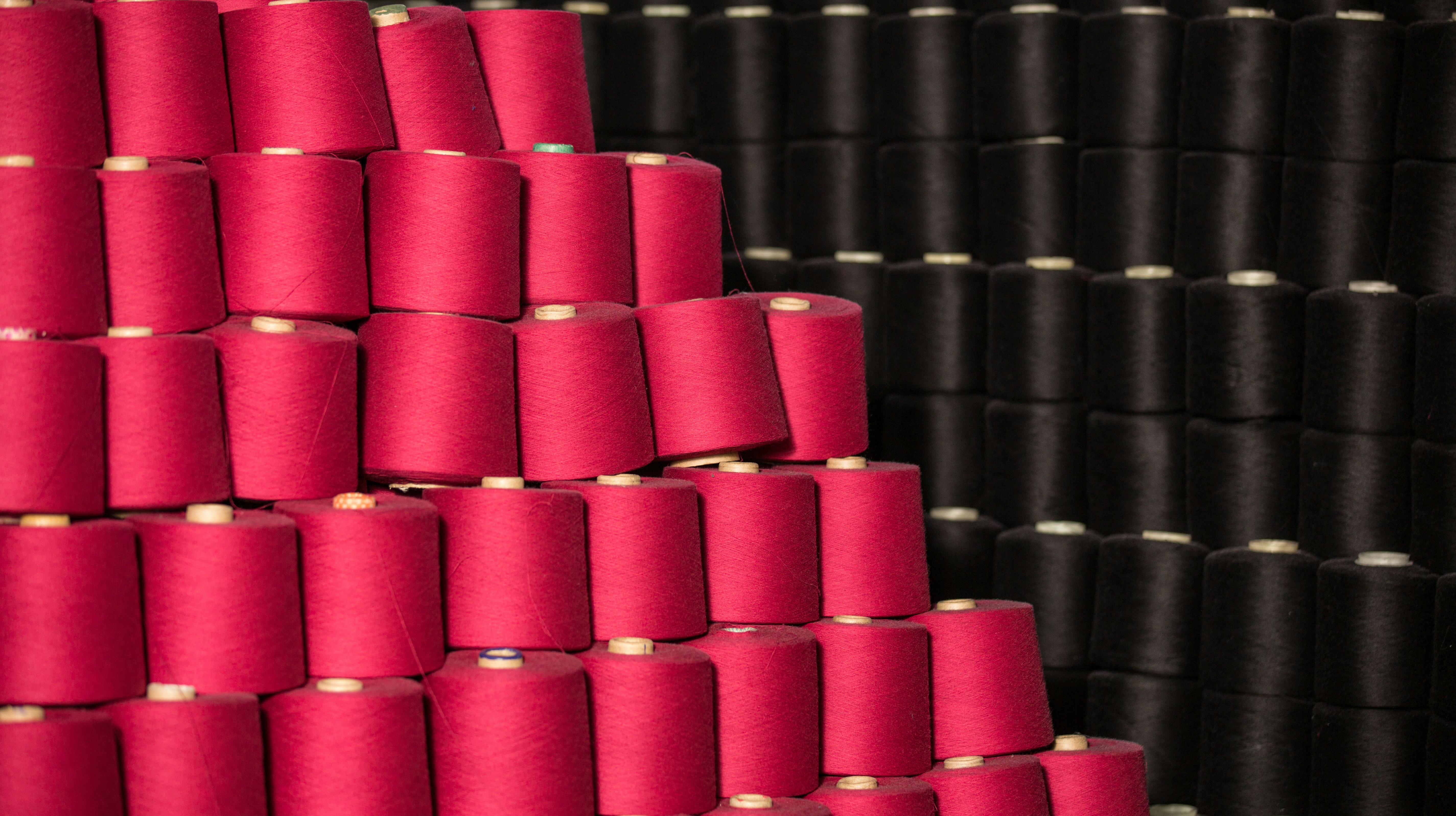 Stacks of vibrant pink and black thread spools.