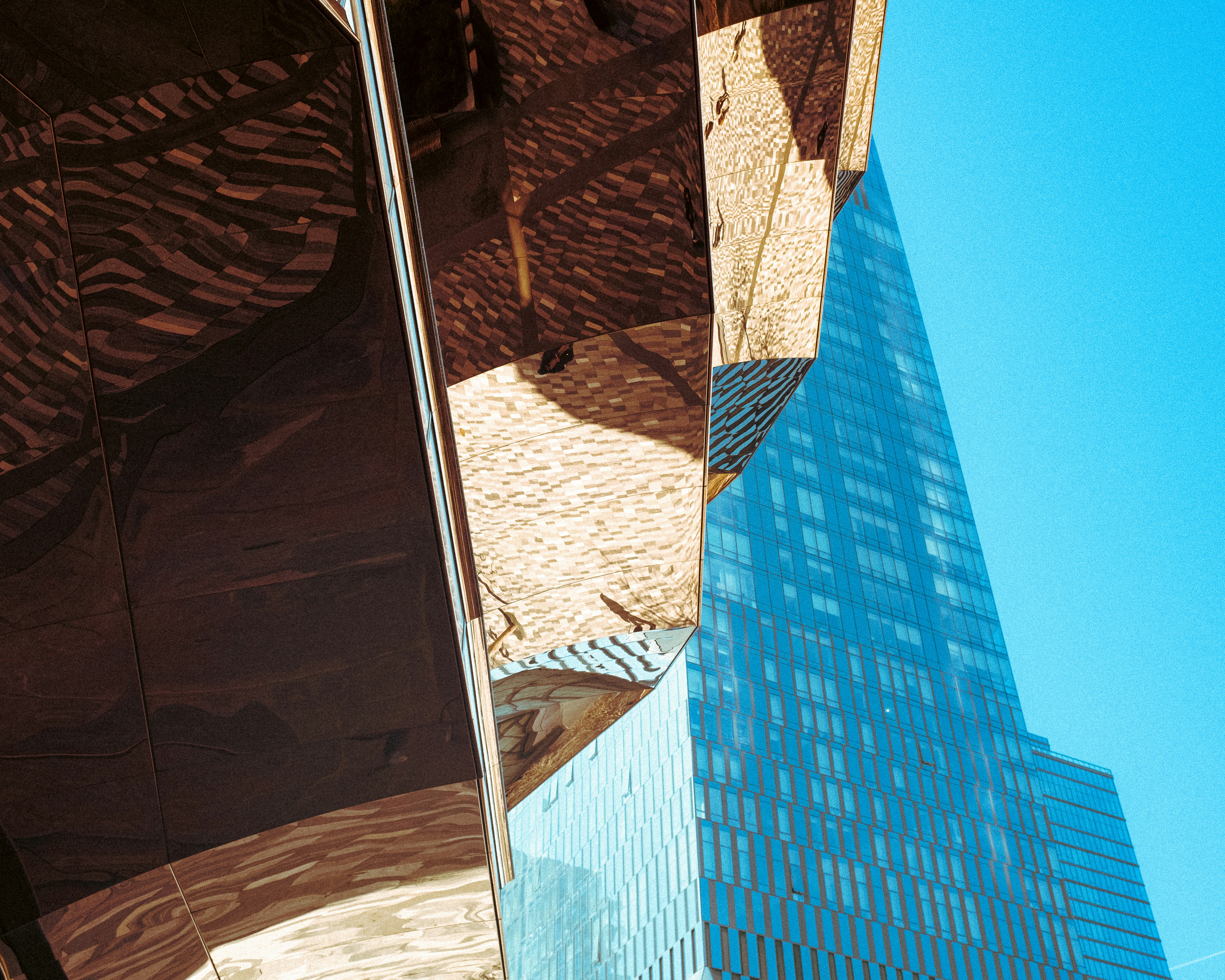 Abstract reflection on a modern building facade against blue sky.