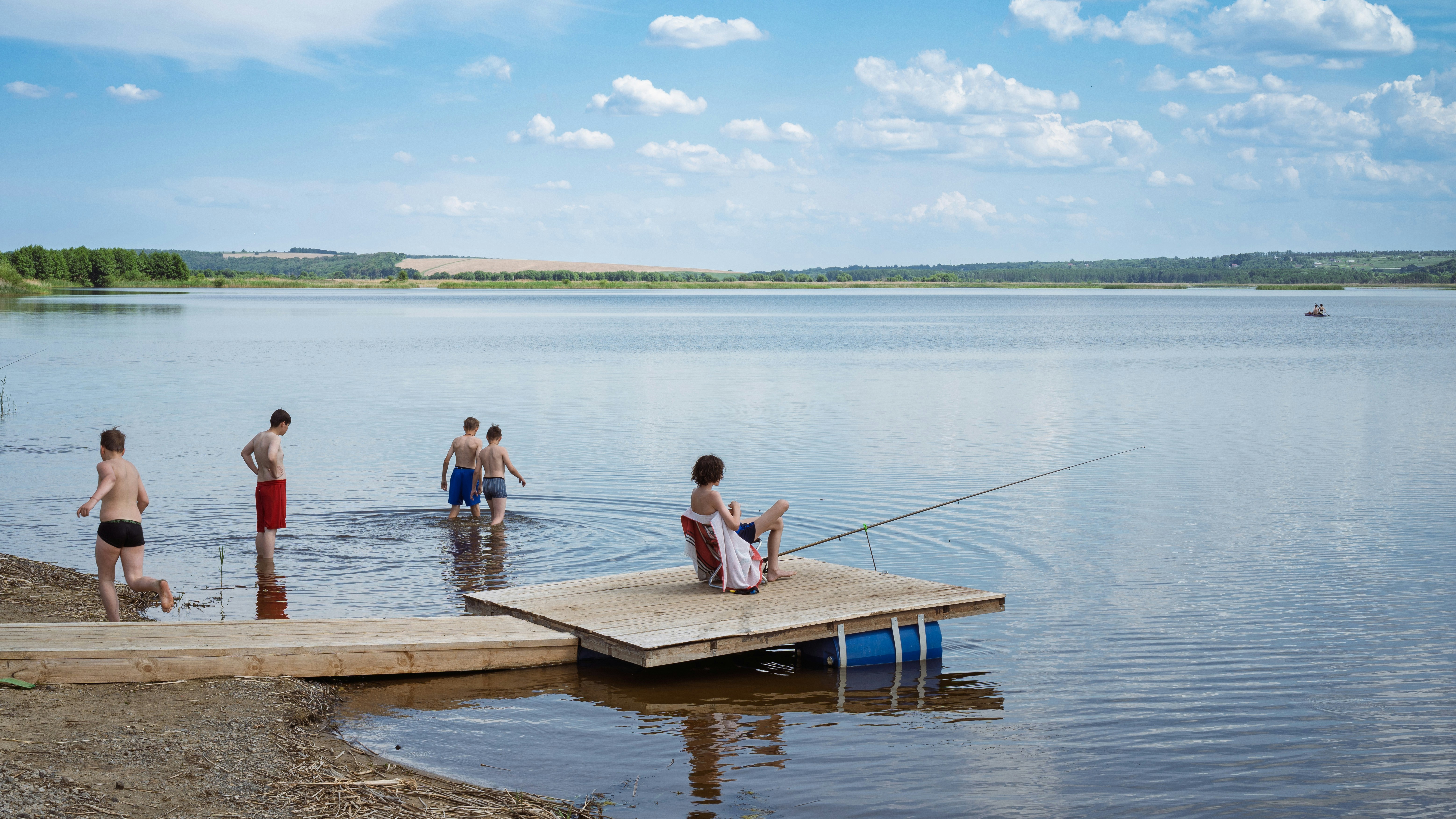 People wading and fishing in a serene lake.