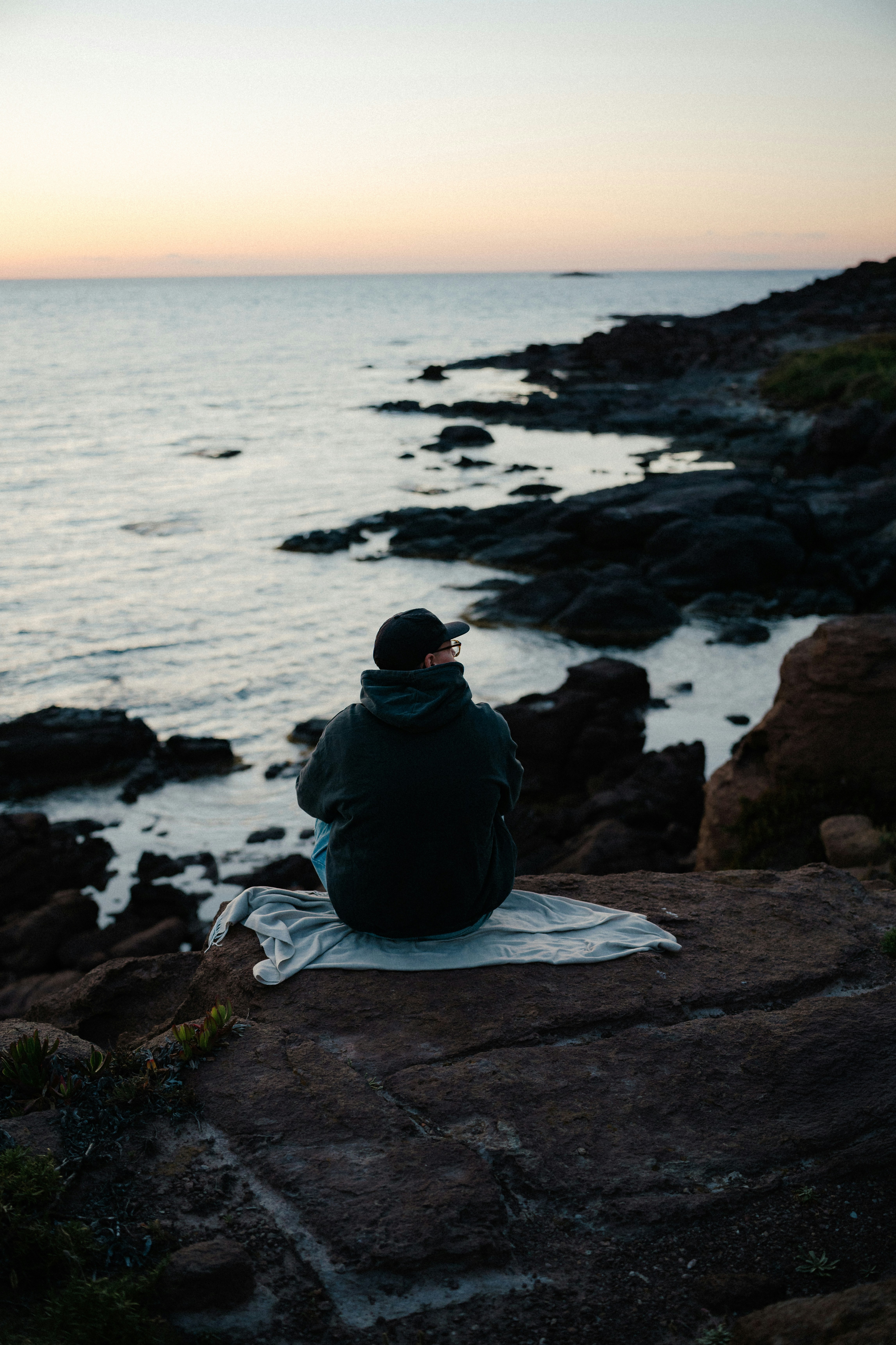 Lone person watching sunset from rocky ocean shore