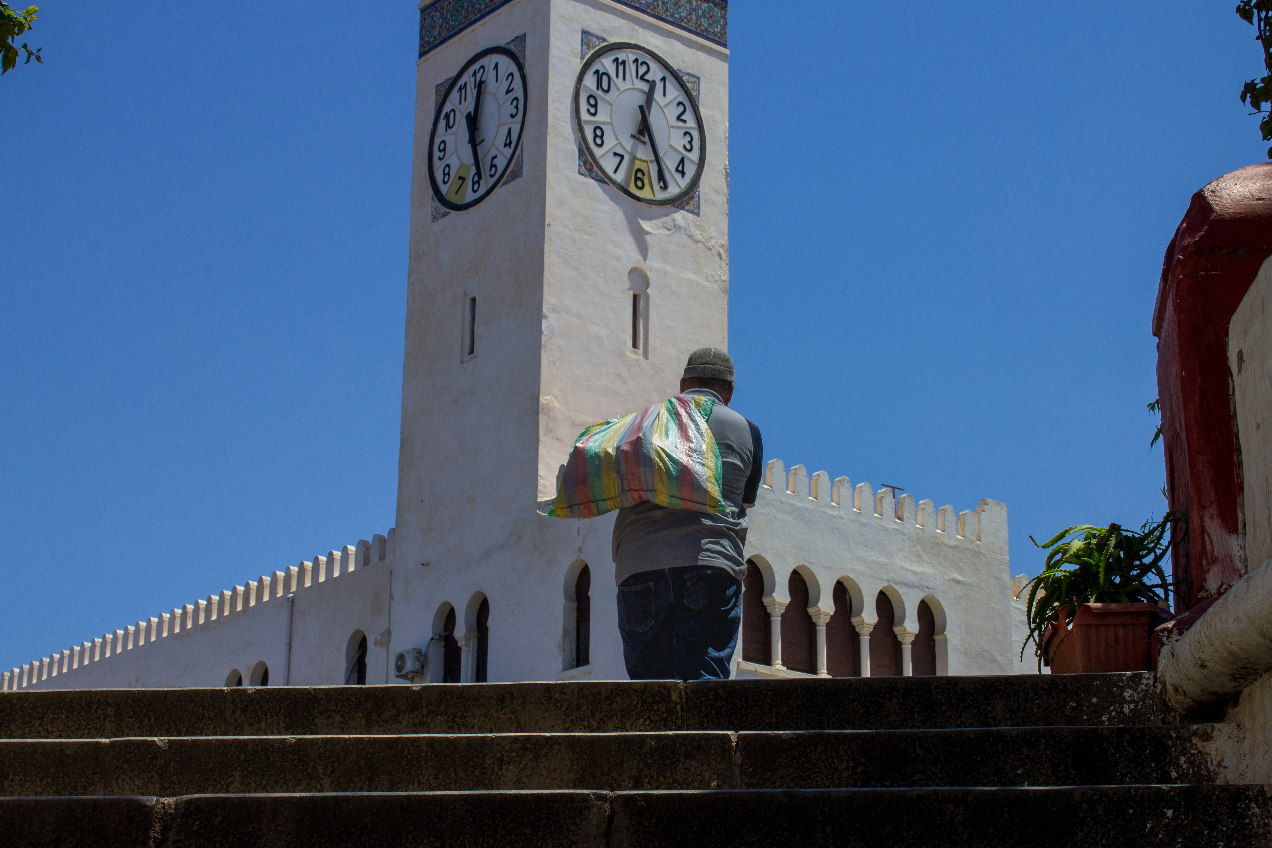 A person walks up stairs towards a white clock tower.