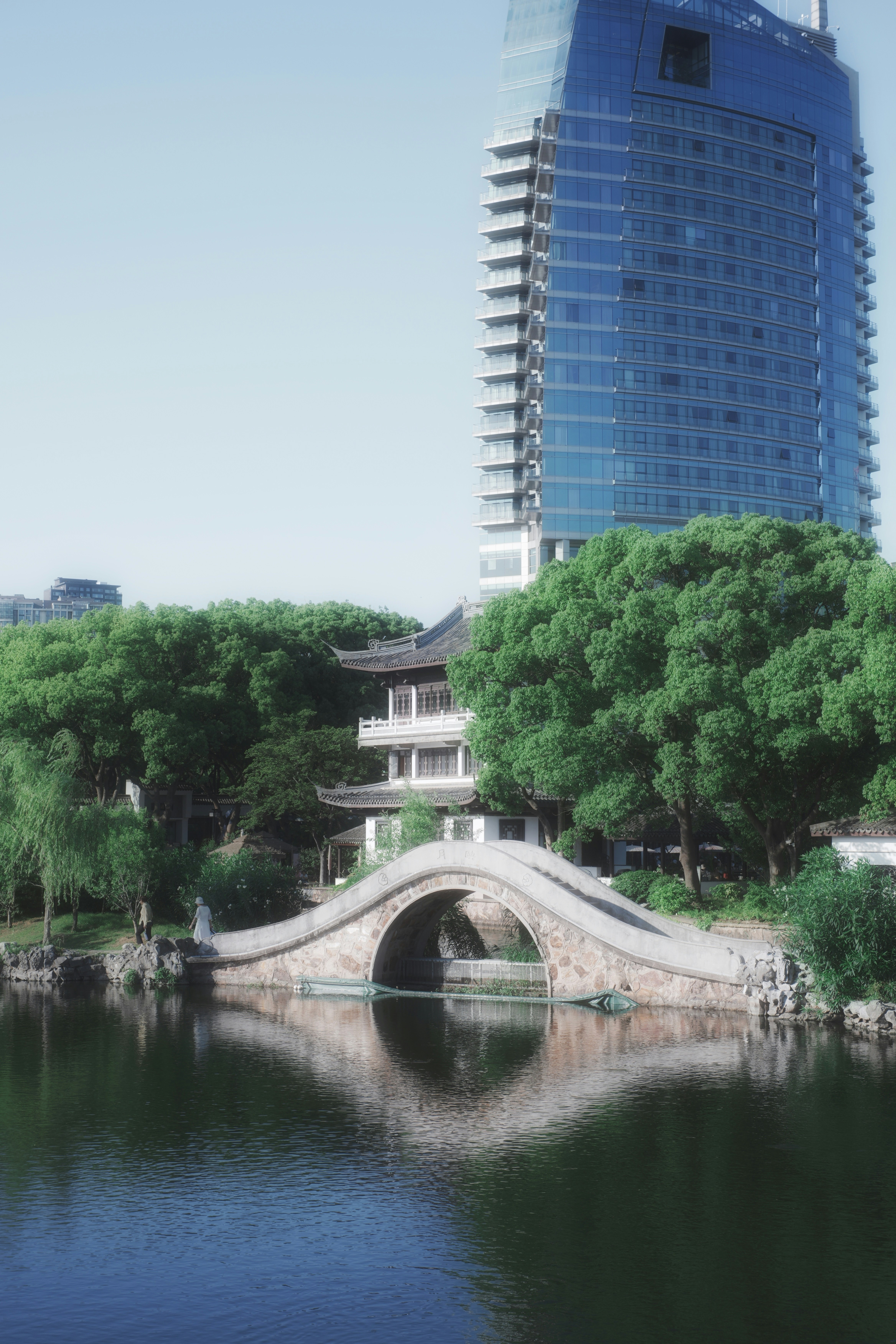 伝統的な石橋、パゴダ、現代の超高層ビルが水面に映っています。