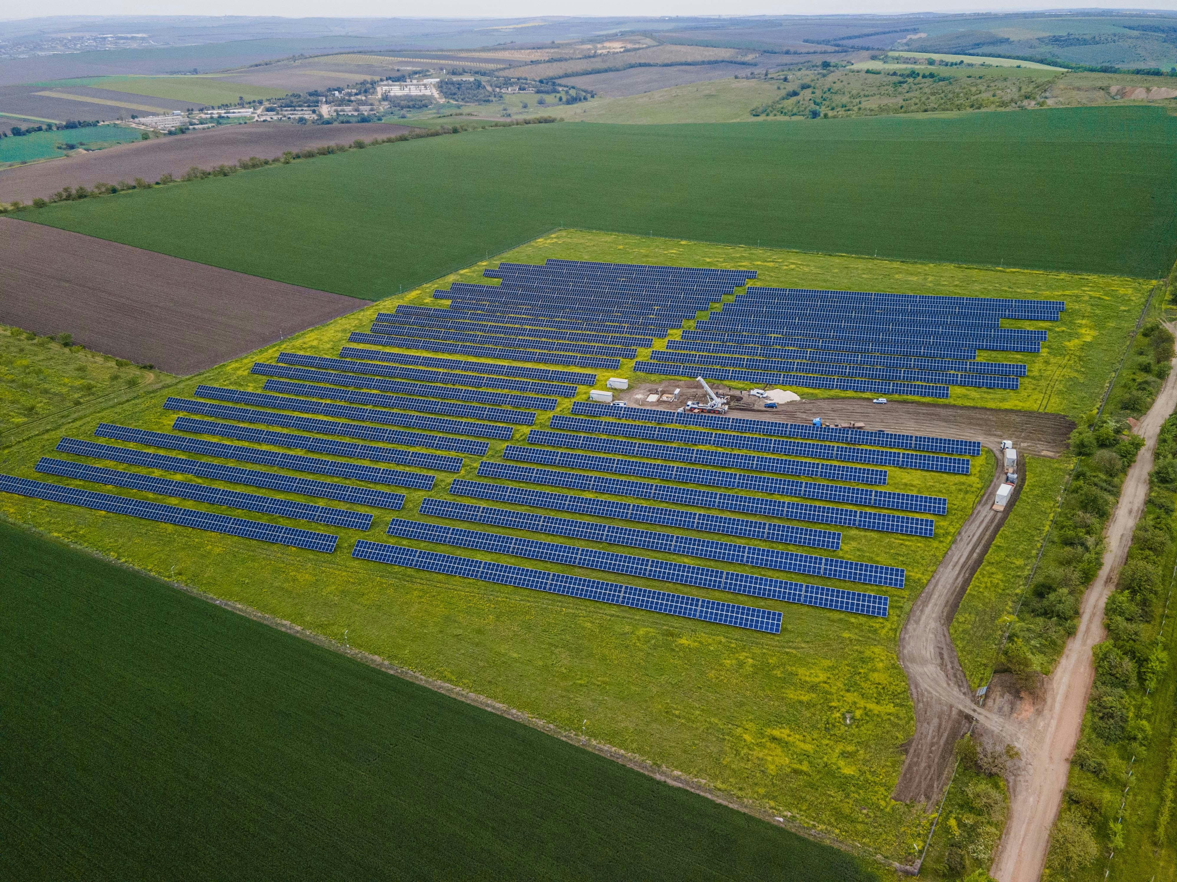 Aerial view of a solar panel farm amidst green fields.