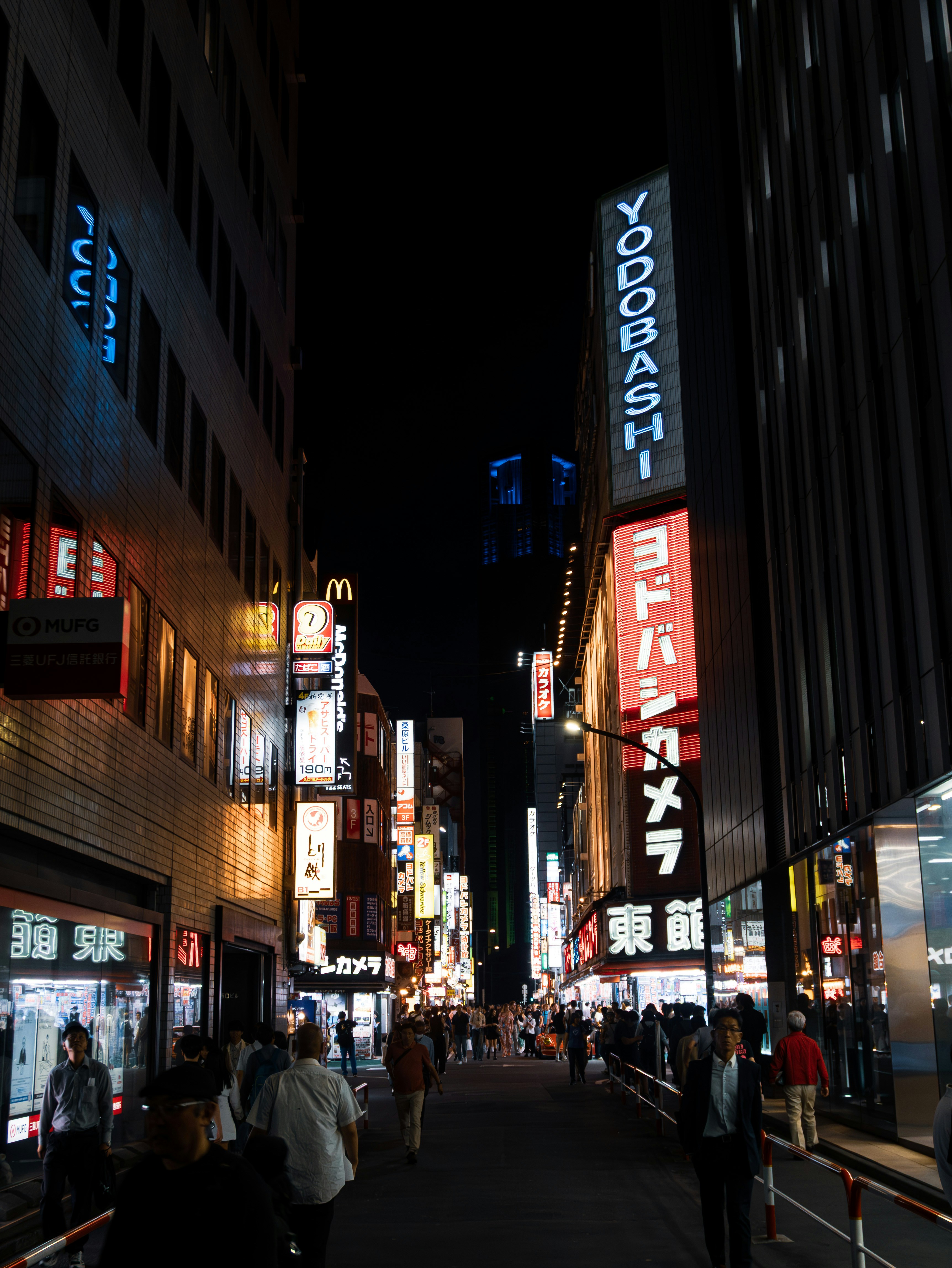 A bustling city street at night with bright neon signs