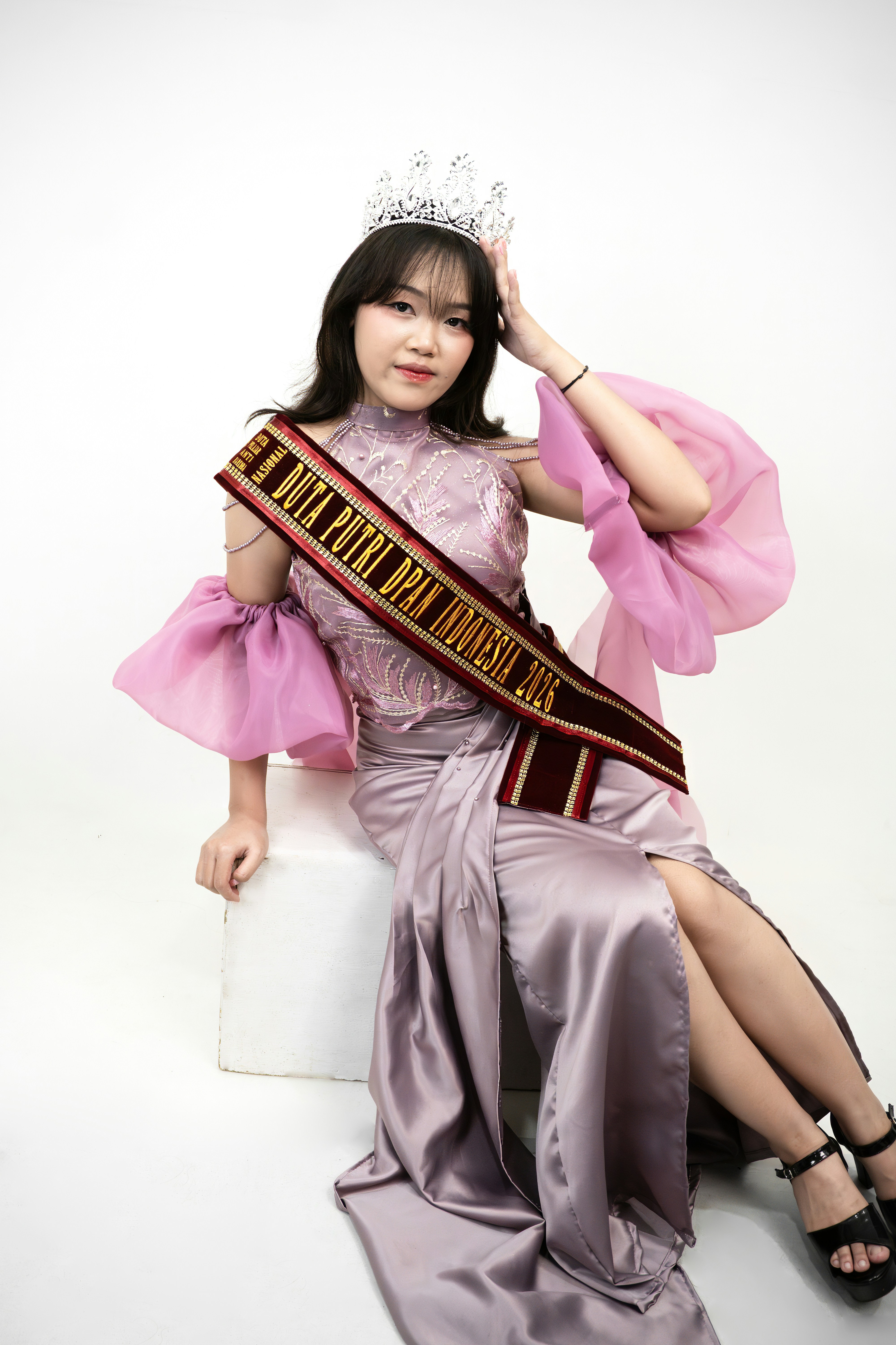 왕관과 허리끈, 보라색 드레스를 입은 우아한 젊은 여성.