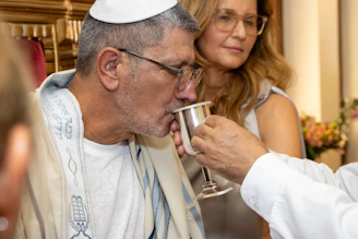 Man in kippah and tallit drinks from a silver cup