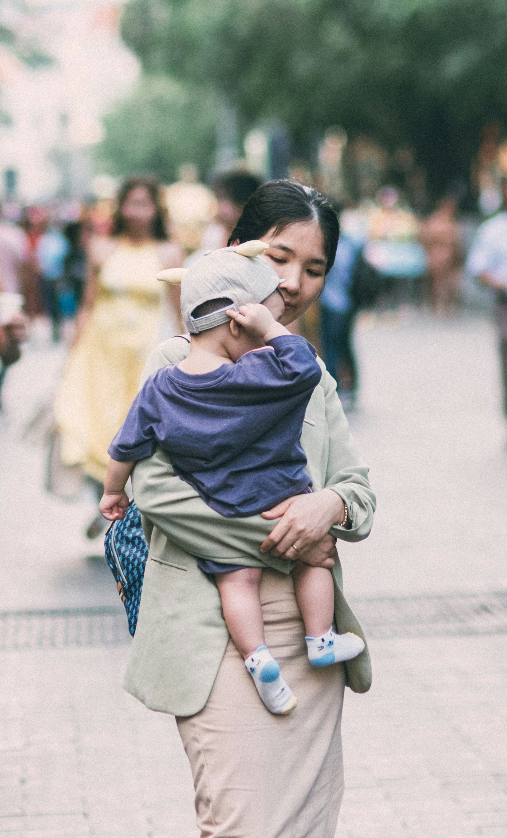 Seorang wanita menggendong seorang anak di jalan yang sibuk.