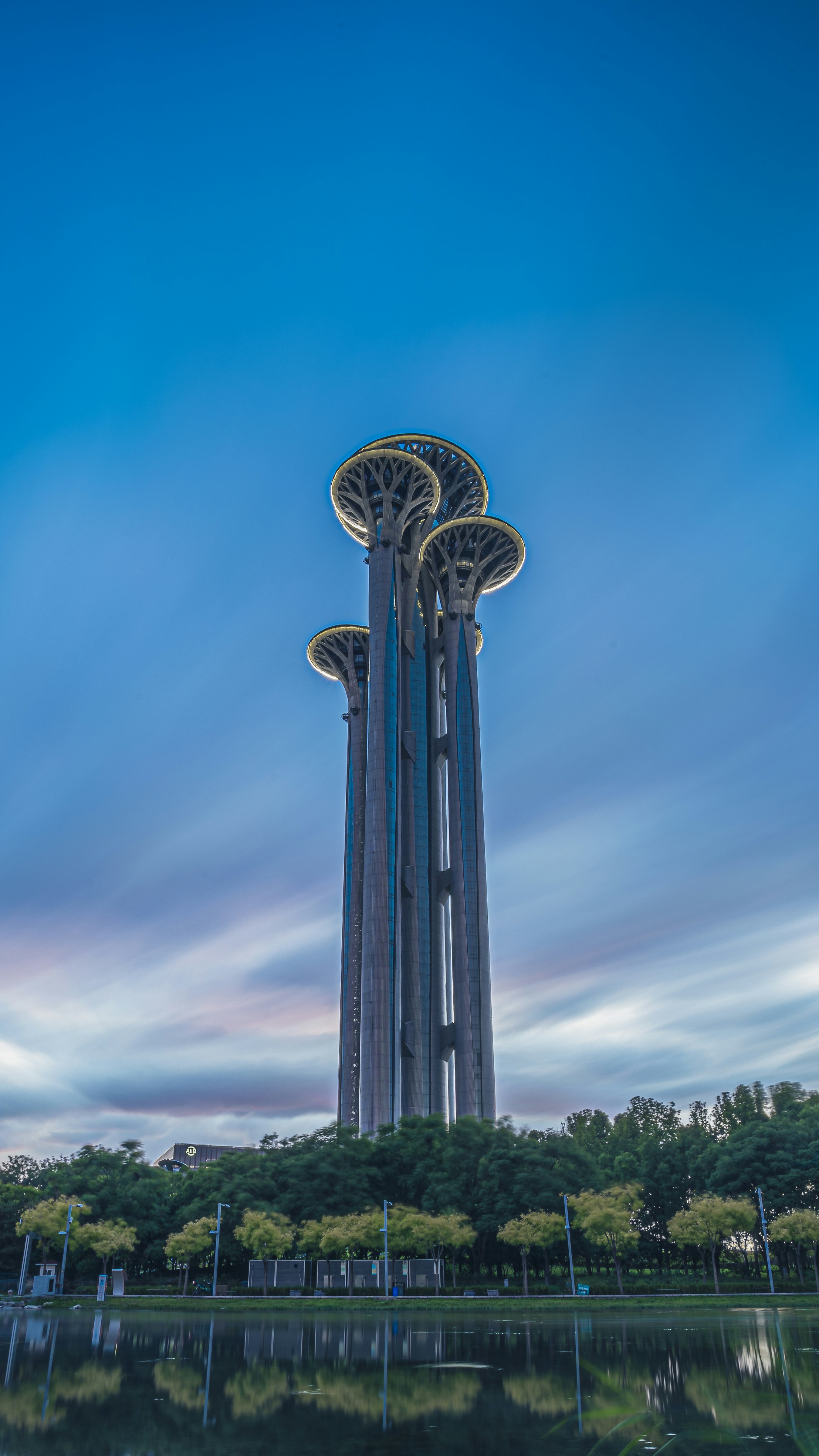 Modern towers with tree-like tops reflecting in water.