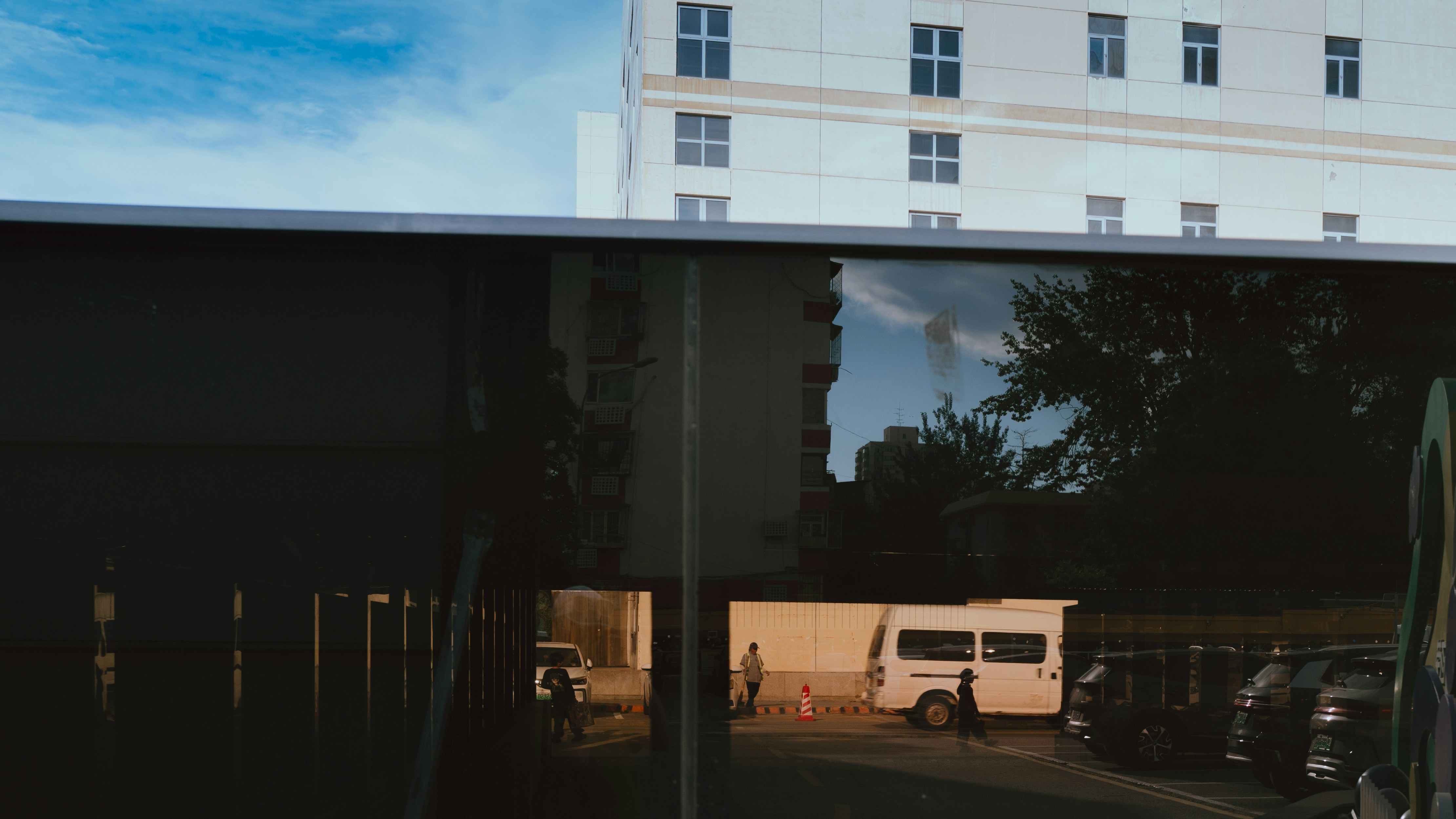 Building and street scene reflected in a dark window.