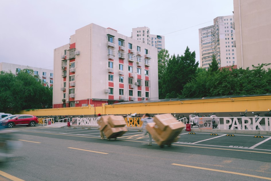 Cardboard boxes on wheels moving past apartment buildings