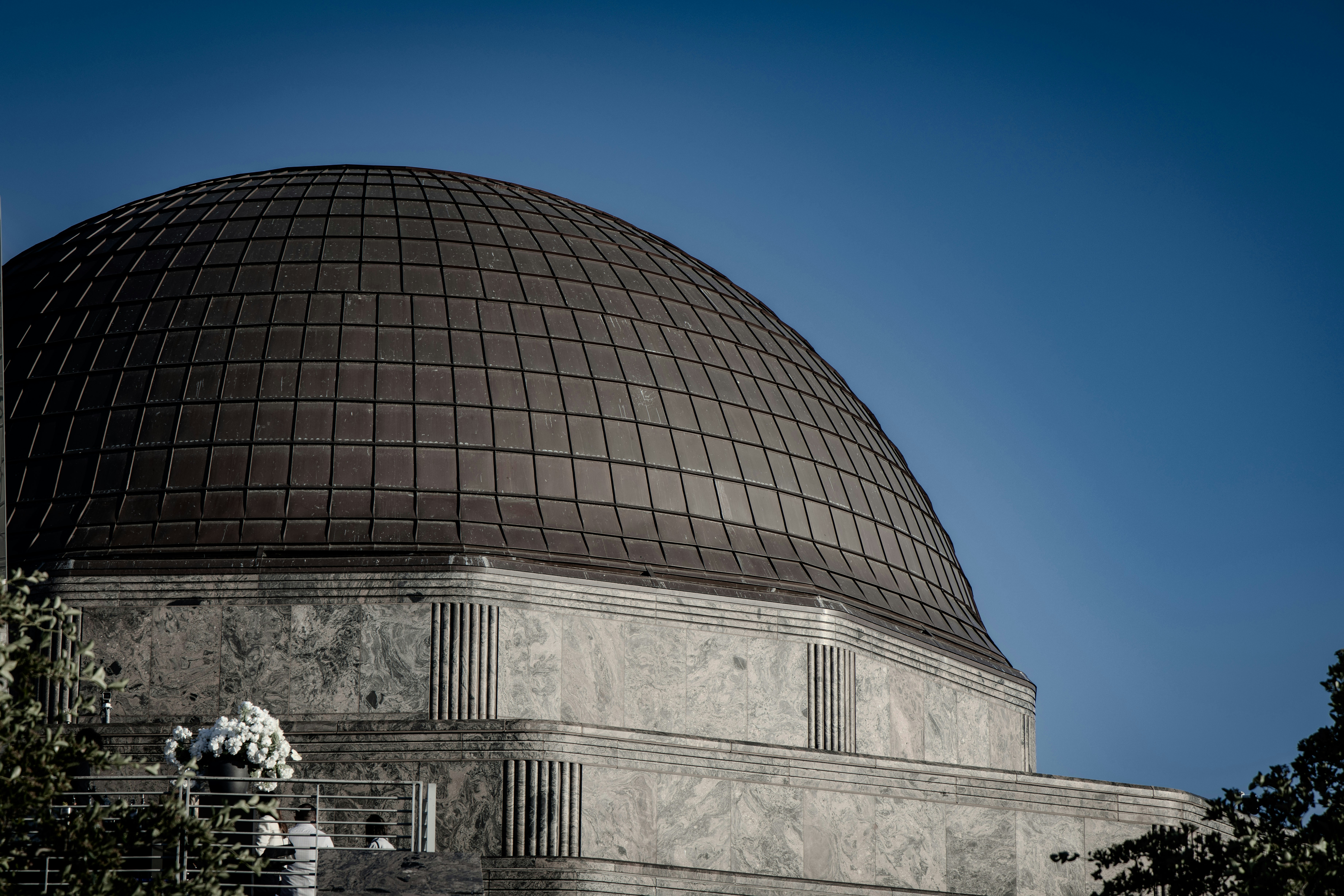 A large, dark dome structure against a clear blue sky.