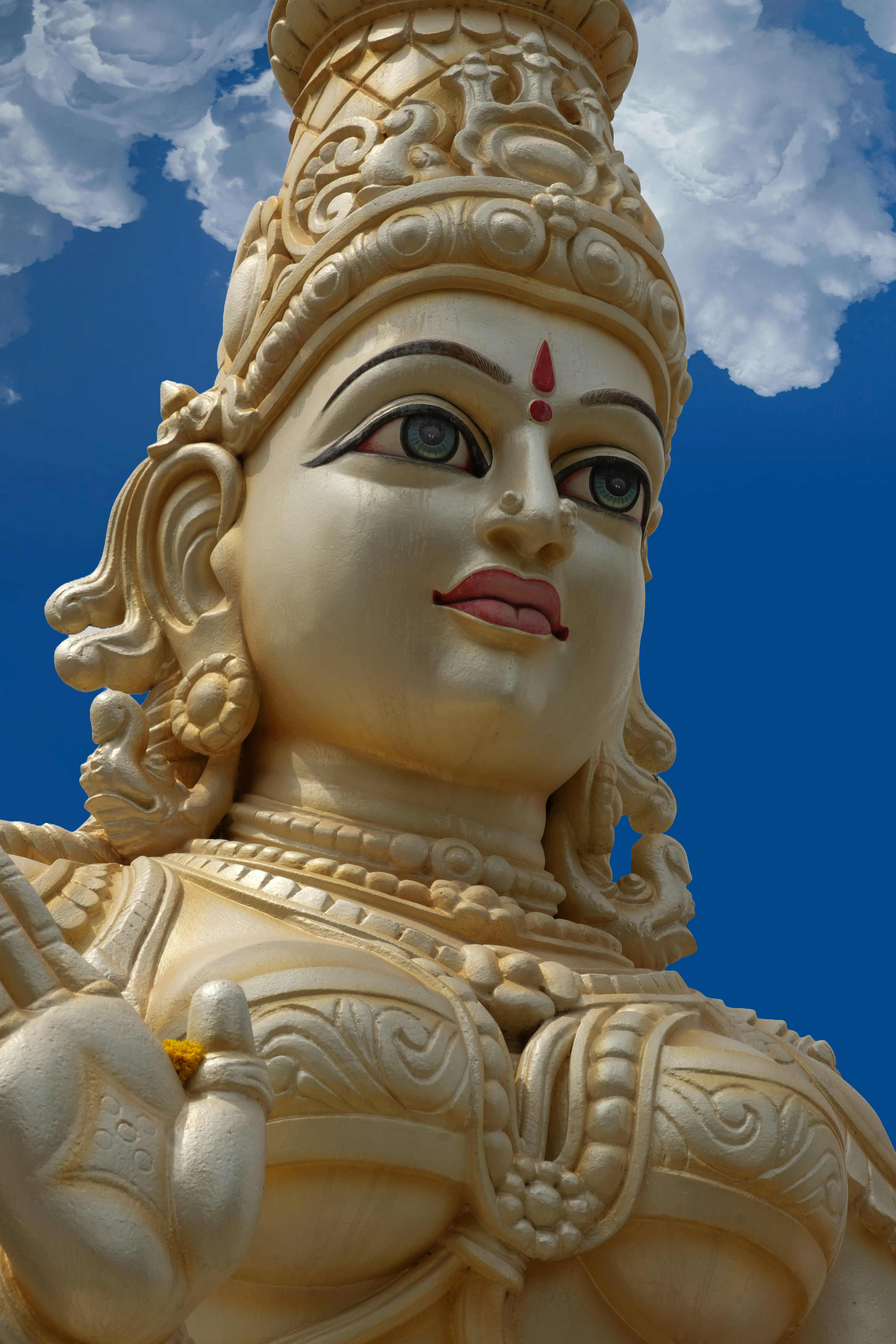 Estátua ornamentada de uma deusa hindu contra um céu azul vibrante