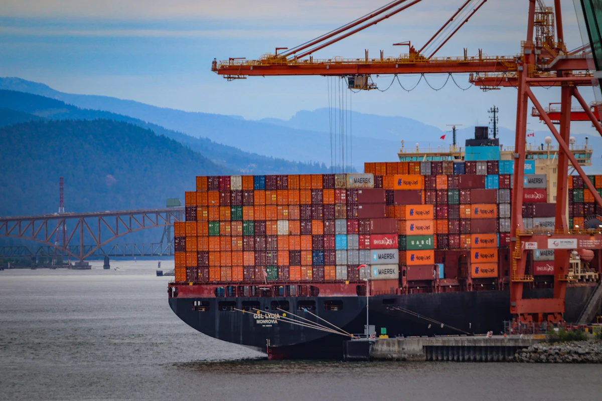 Container ship with gantry cranes near Vancouver, Canada, framed by coastal mountains