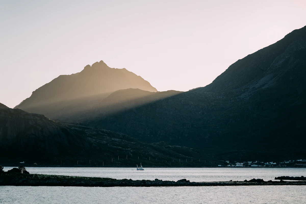 A sailboat on calm water beneath mountain peaks
