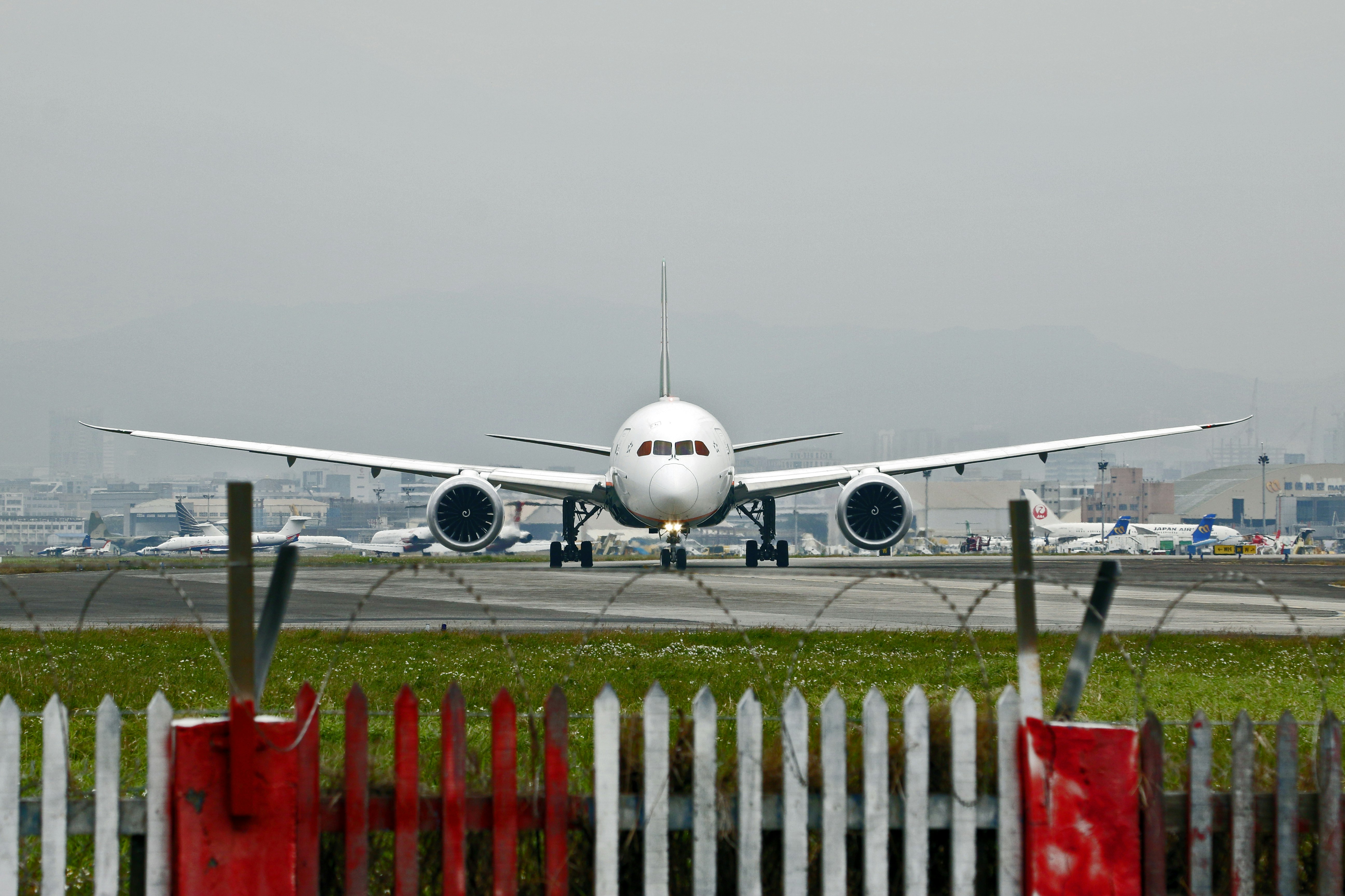 White airplane on a runway with a fence.