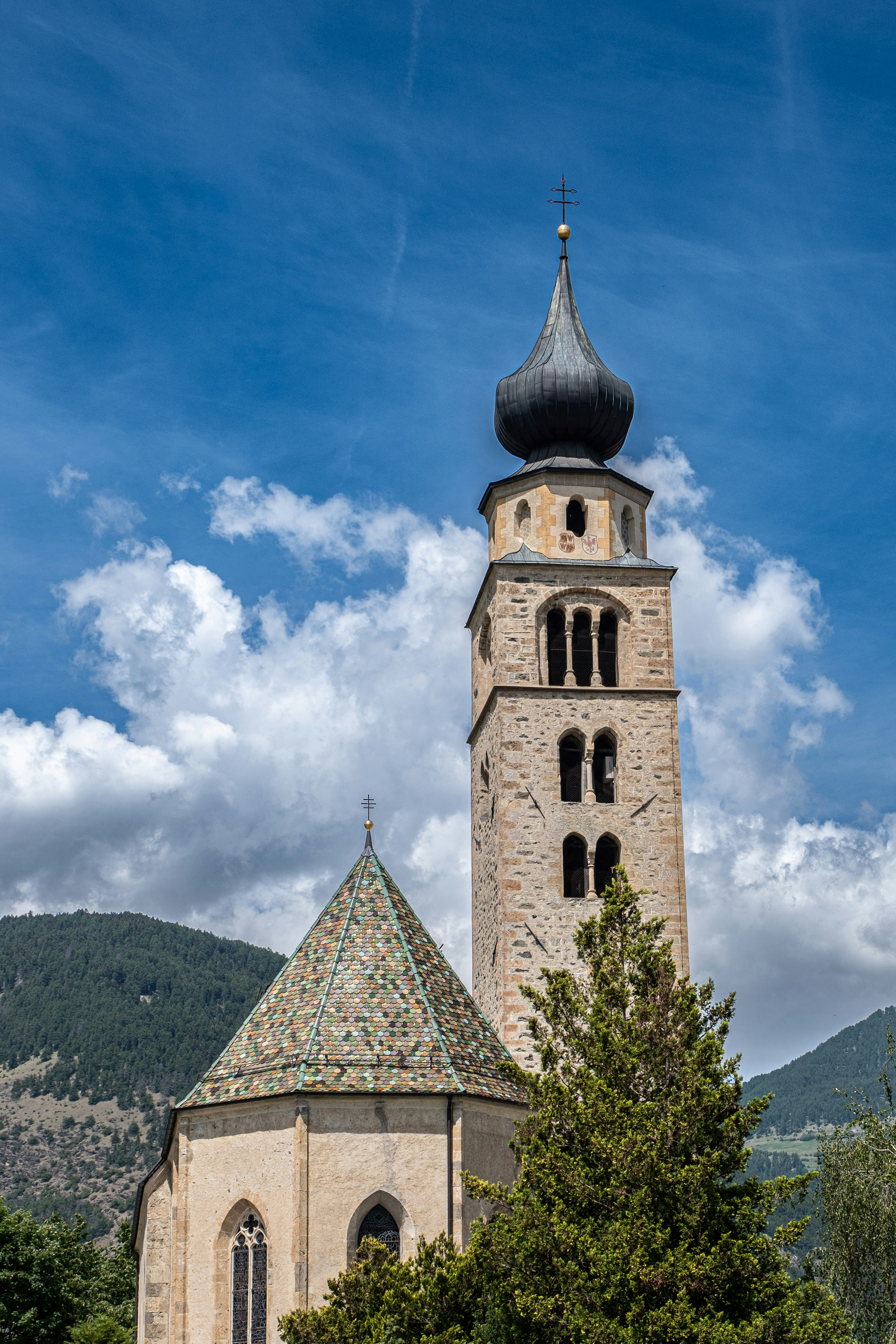 The Parish Church of St Pancras on the outskirts of the historic medieval town of Glurns/Glorenza in the Vinschgau/Val Venosta Valley of the South Tyrol, Italy. The bell tower is from the original Romanesque parish church, first mentioned in 1227, the old nave with the choir having been replaced by a later Gothic construction, with distinctive coloured tiles. The Baroque onion dome dates from the late 17th century.