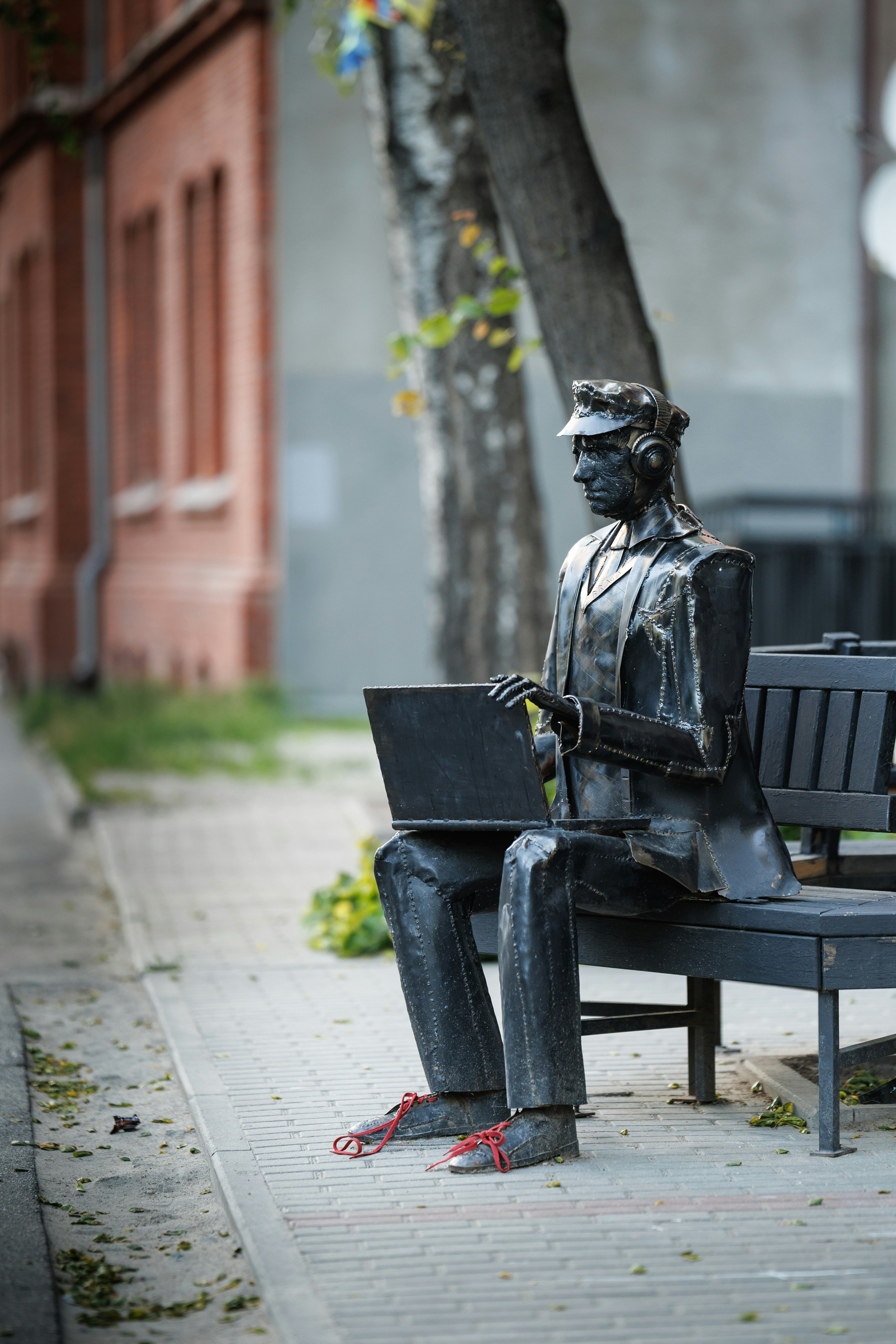 Metal statue of a man working on a laptop.