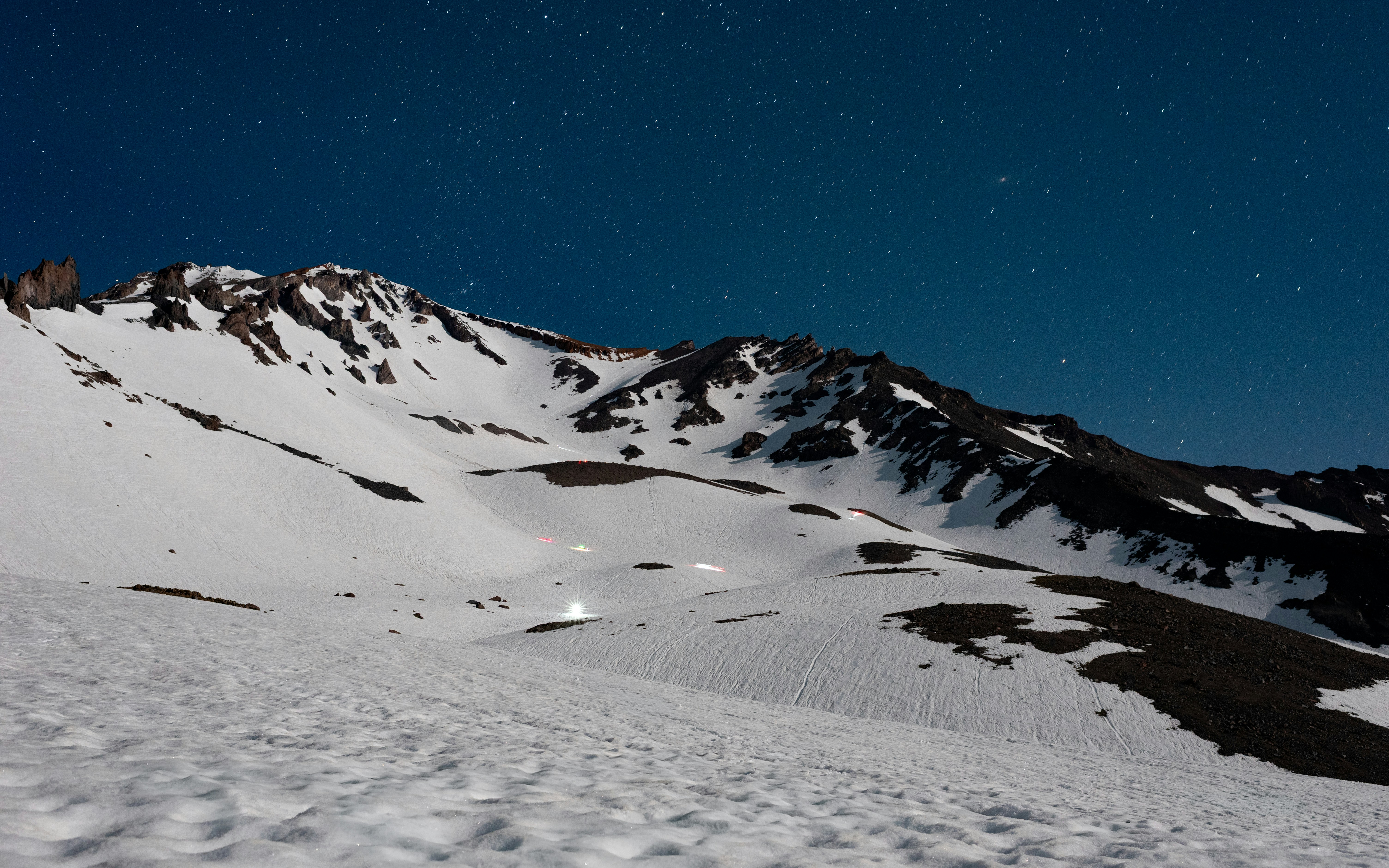Snowy mountain peaks under a vast, starry night sky.
