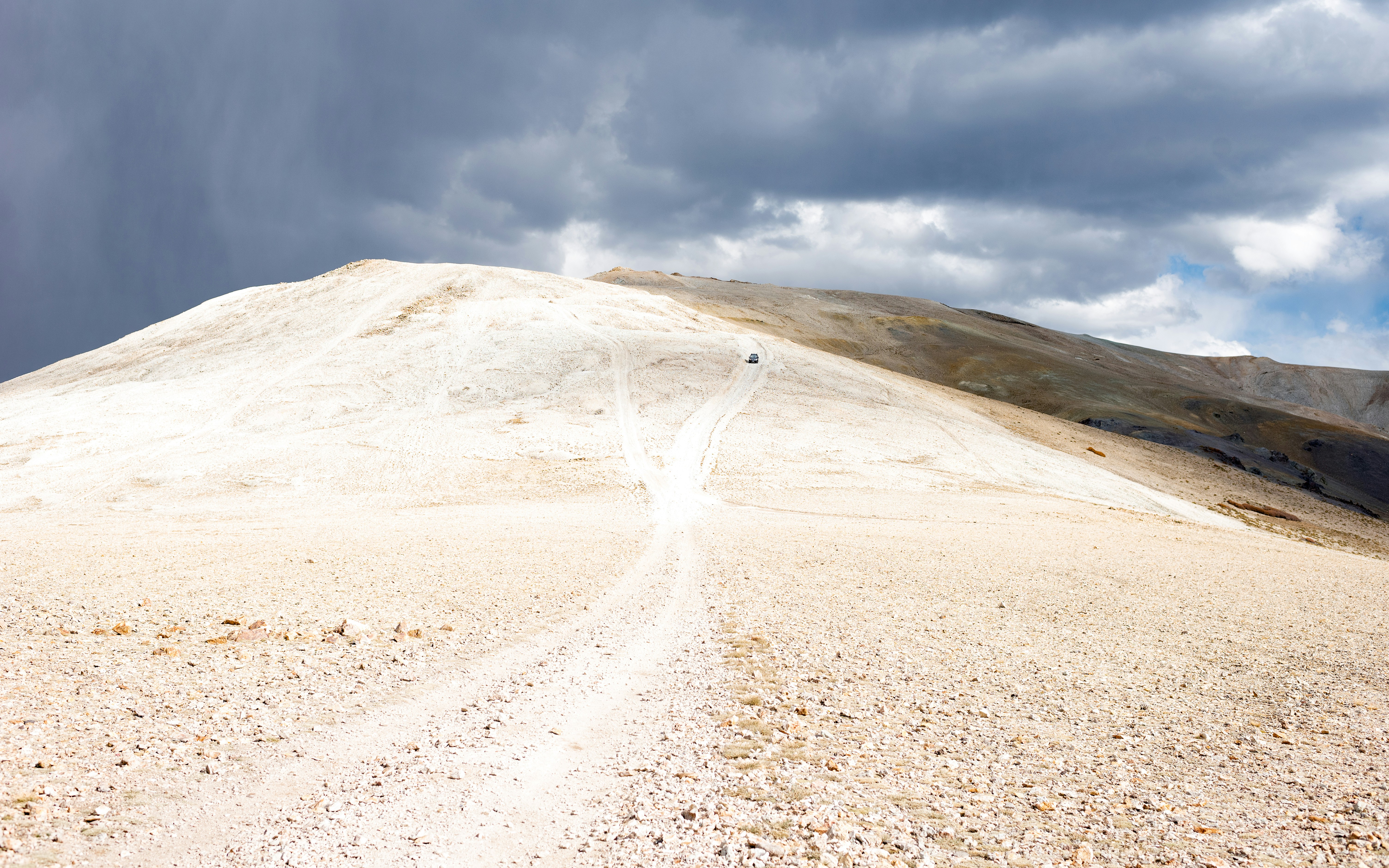 A desolate mountain trail under a cloudy, dramatic sky.