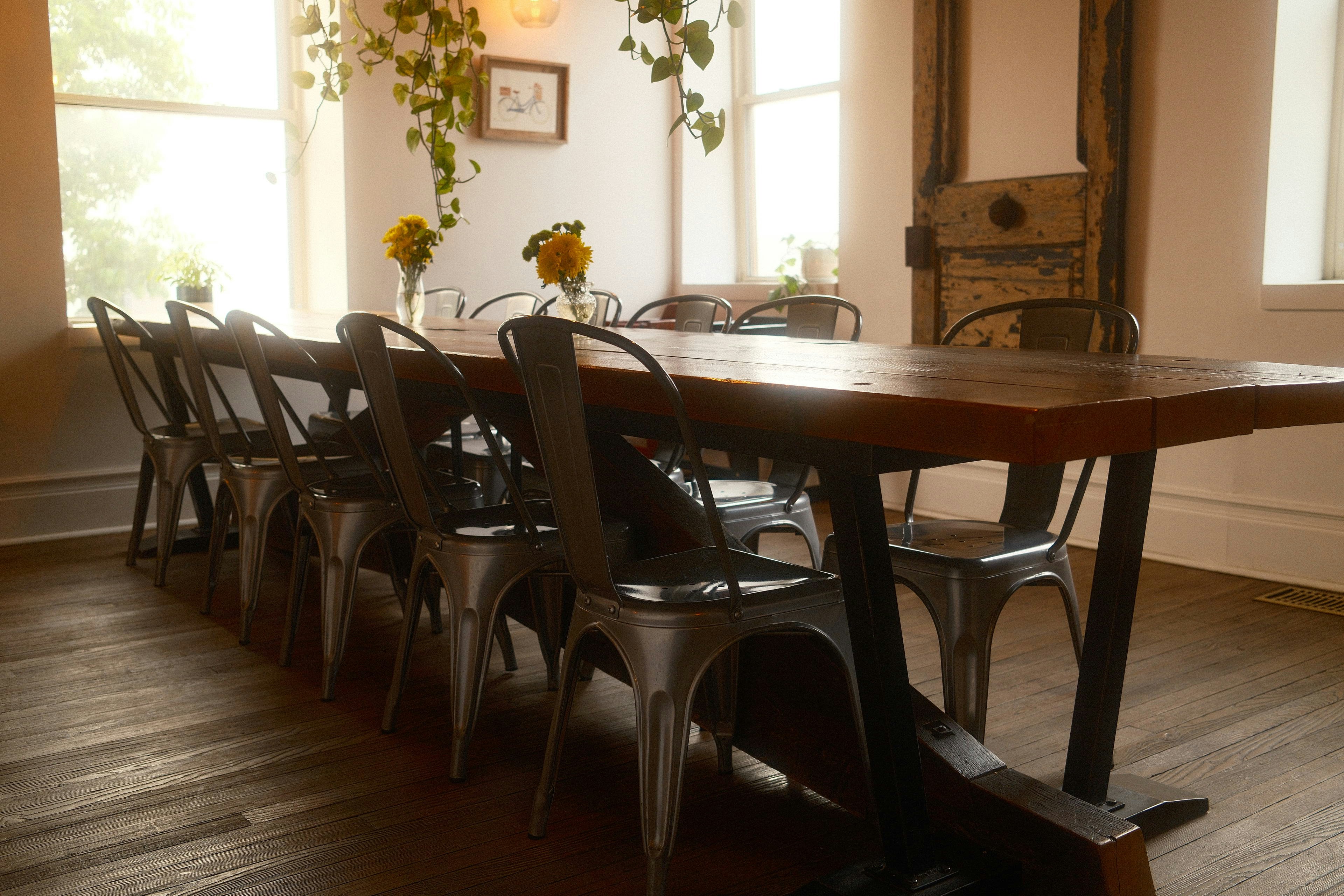 Long wooden dining table with metal chairs in bright room.