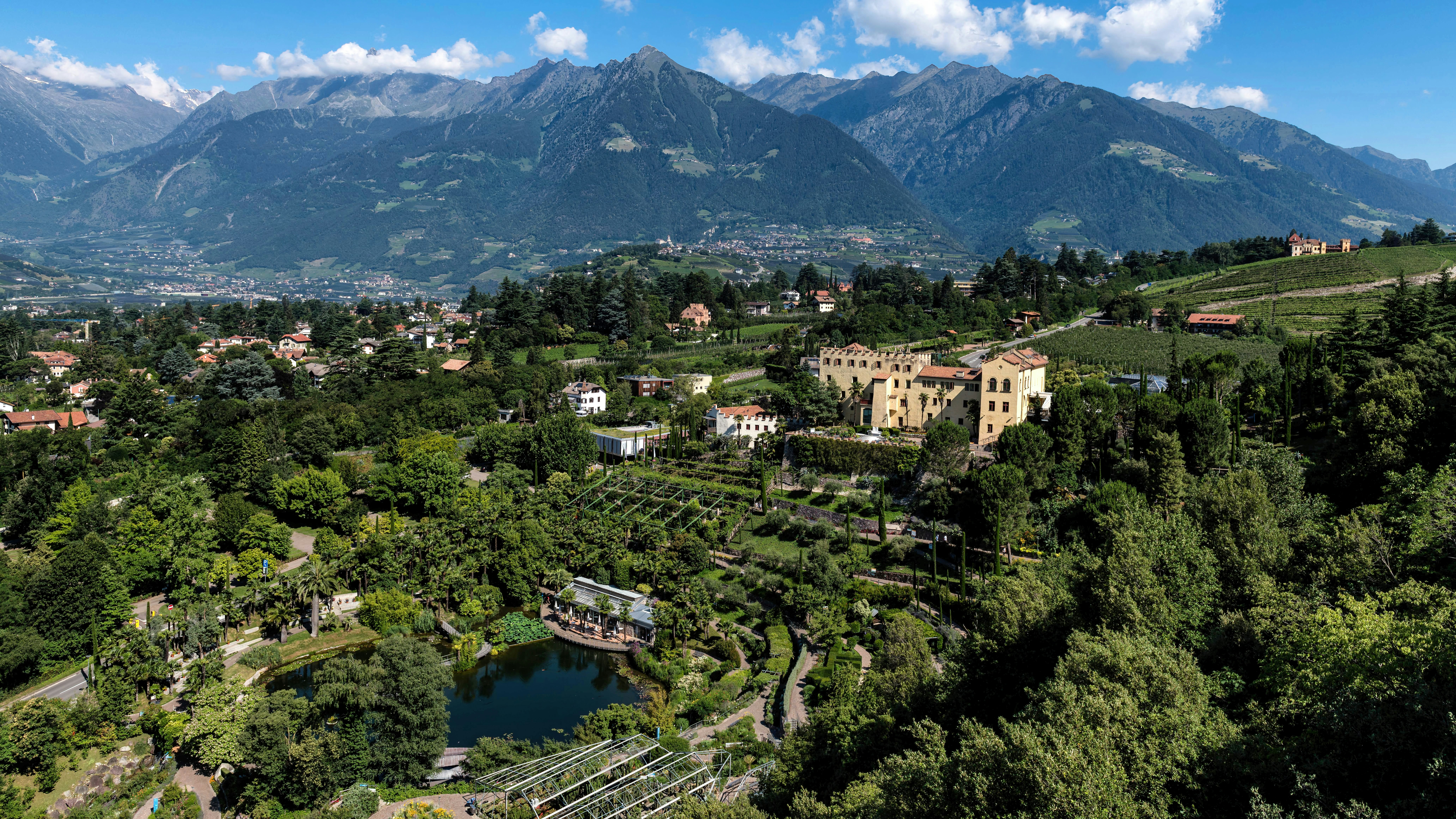 Historic villa amidst green gardens and towering mountains.