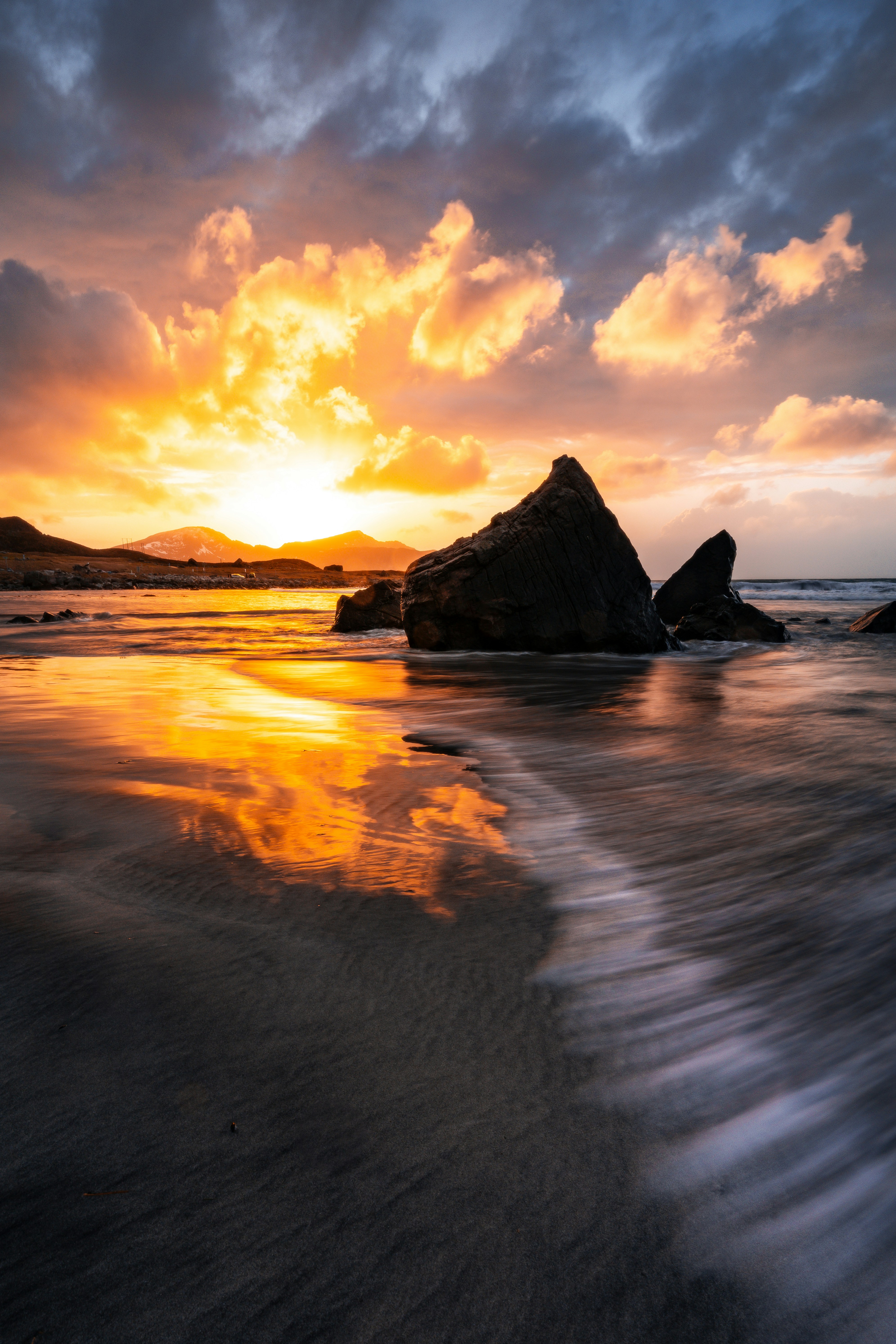 A dramatic sunset over a rocky beach with waves.