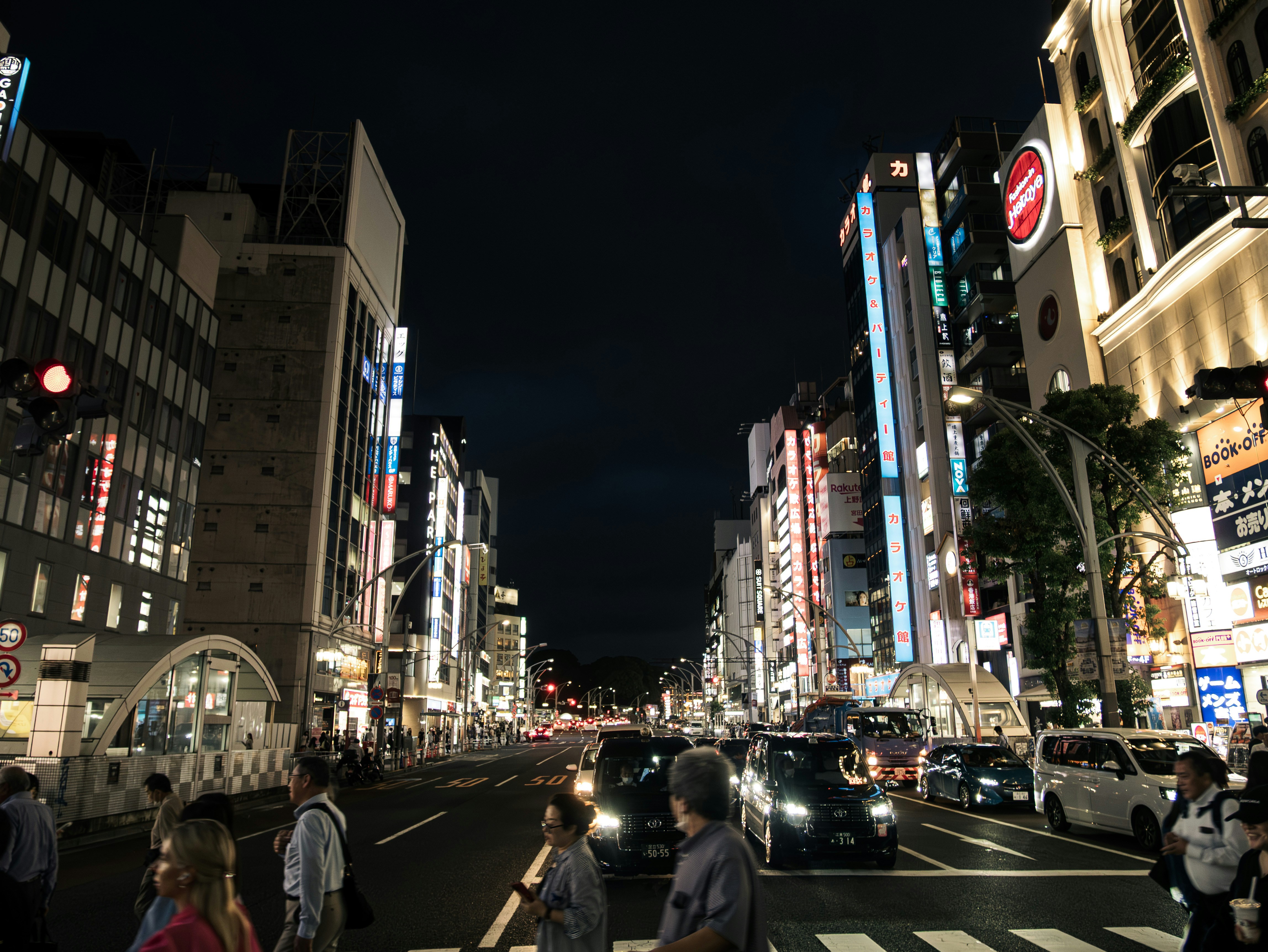 Nighttime cityscape with illuminated buildings, cars, and pedestrians