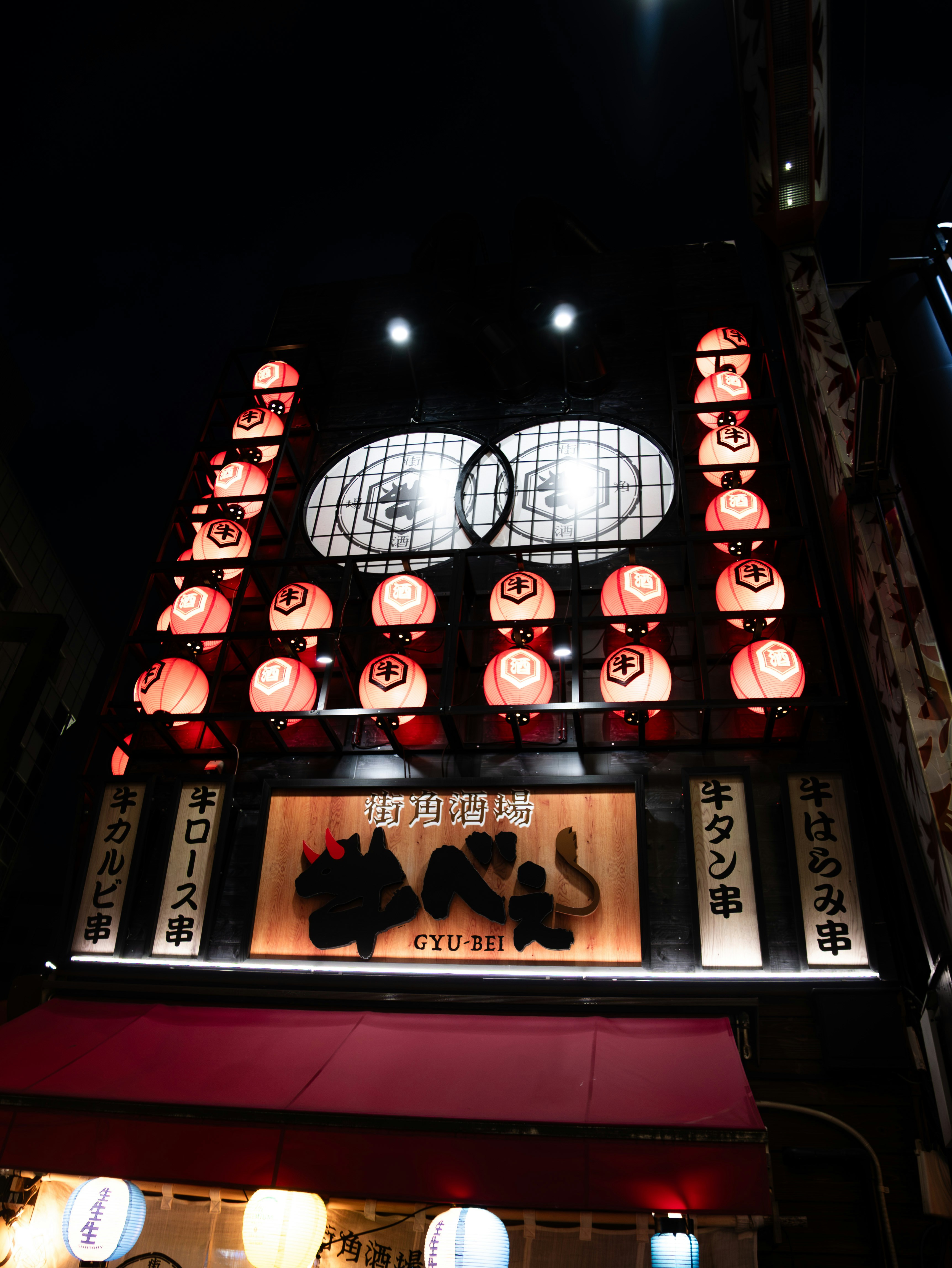 A japanese building adorned with many red lanterns at night