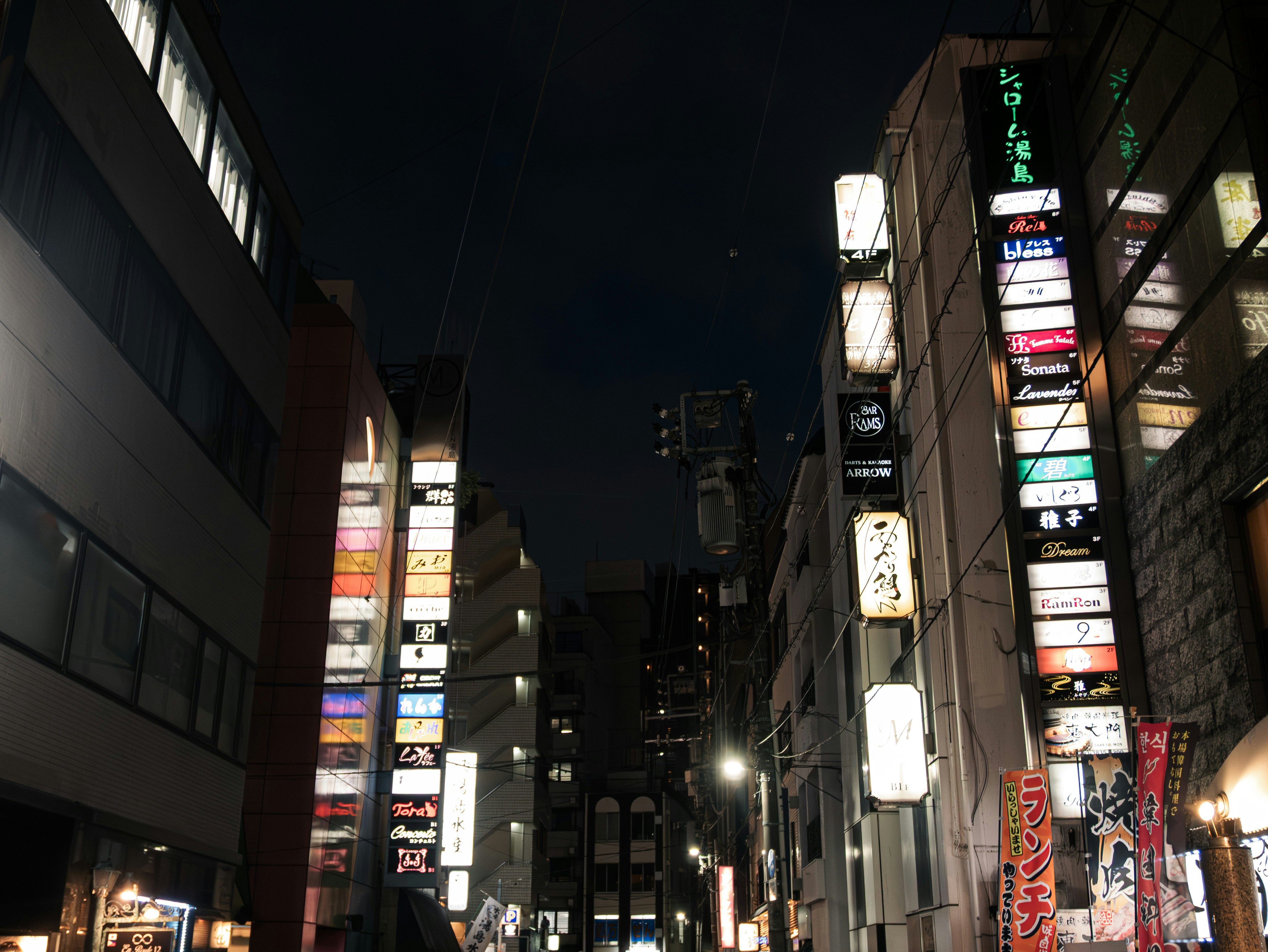 Tall city buildings illuminated by numerous vibrant signs at night