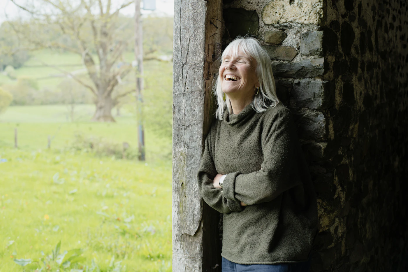 A woman in her sixties laughing in an open stone doorway