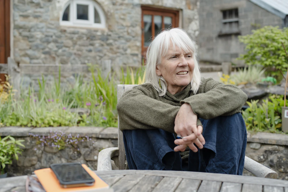 Senior woman sitting quietly alone at an outdoor table with her phone